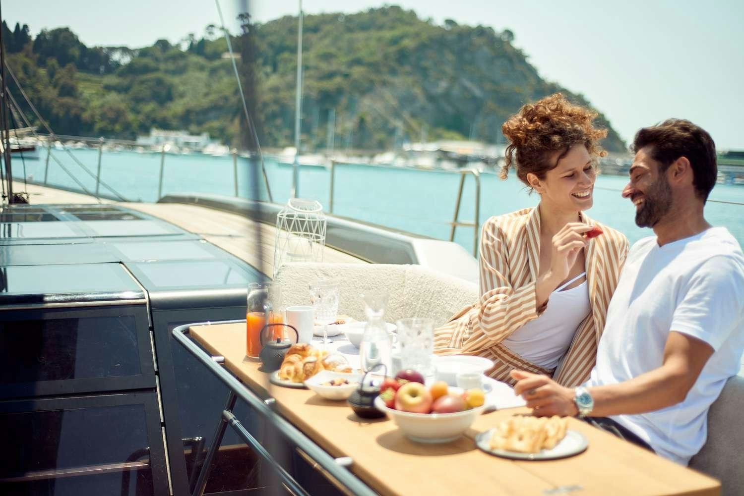 a man and a woman sitting at a table with food on it aboard AORI Yacht for Charter