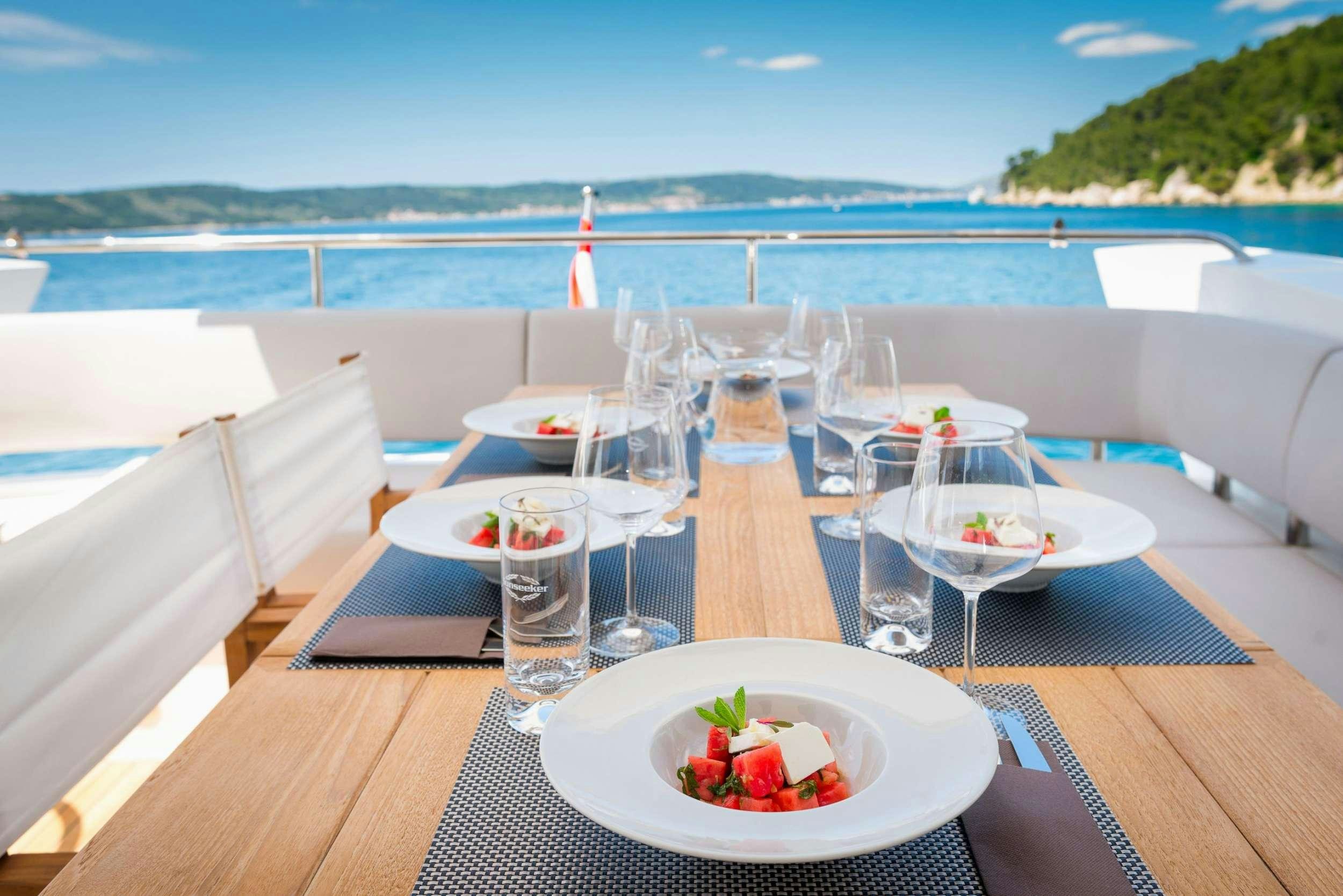 a table with plates and glasses on it next to a body of water aboard HIDEAWAY Yacht for Charter