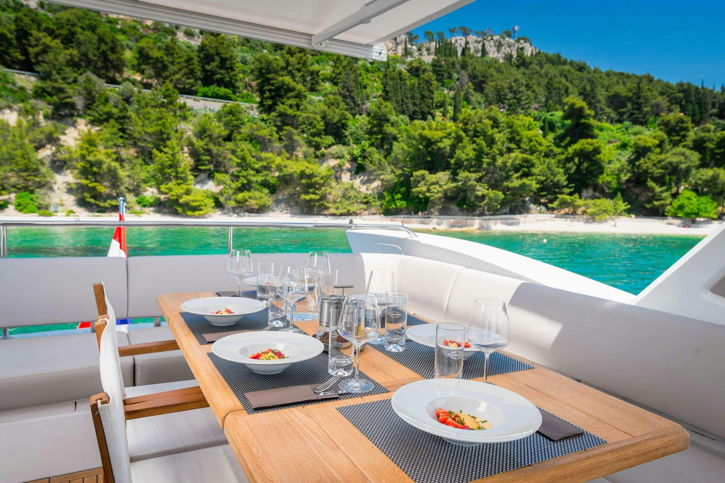 a table with wine glasses and a view of a lake aboard HIDEAWAY Yacht for Charter