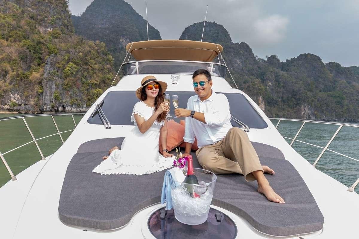 a man and woman sitting in a convertible car with a mountain view aboard 137 PILLARS SPIRIT Yacht for Charter