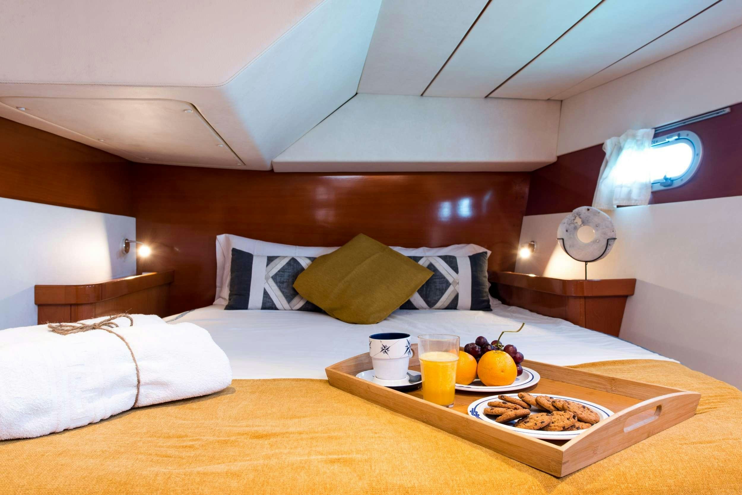 a bed with a tray of food and drinks on it aboard JOVA Yacht for Charter