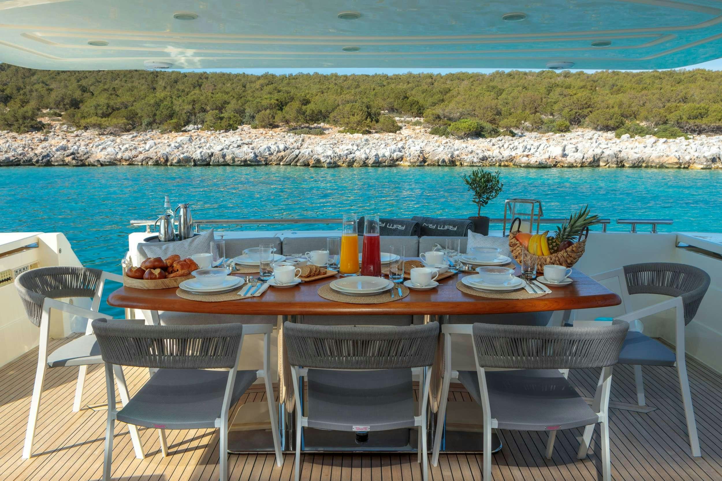 a table set for a meal on a balcony overlooking a body of water aboard MY WAY Yacht for Charter
