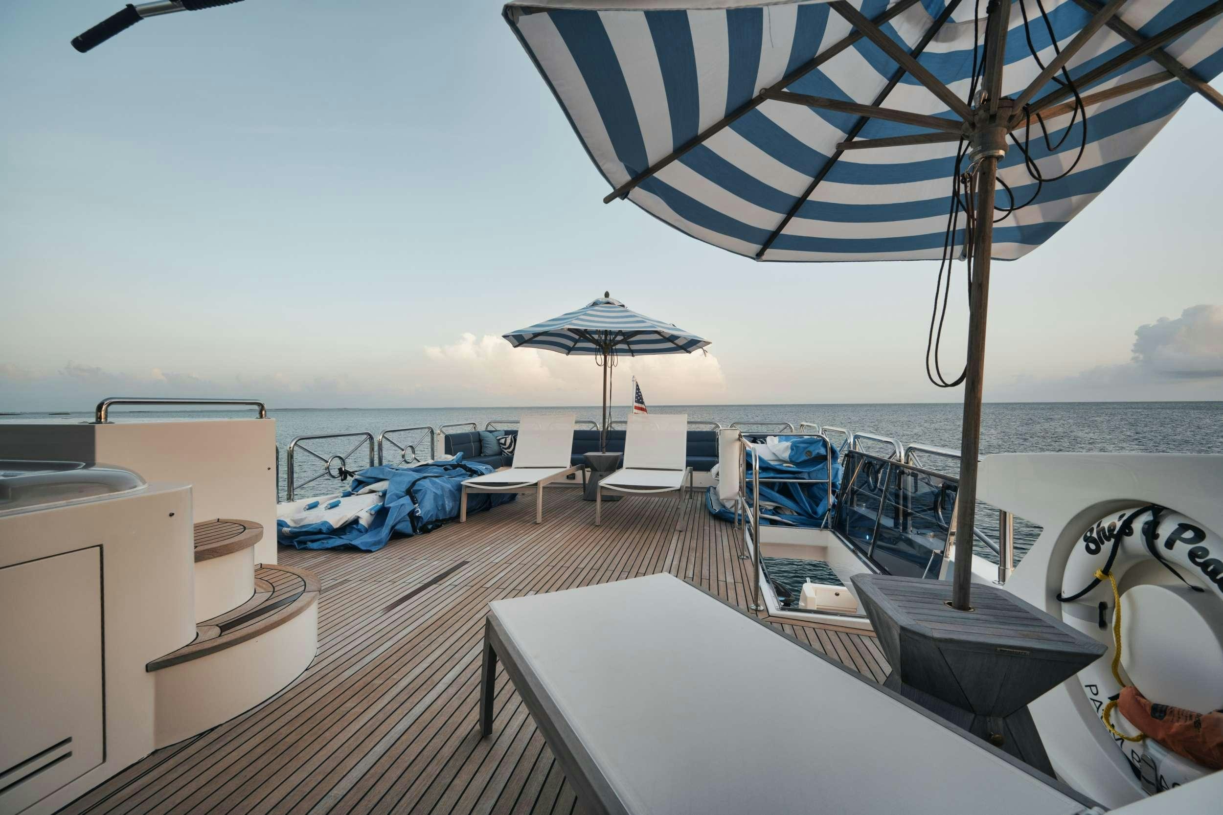 a deck with a large umbrella and chairs on it aboard SHE'S A PEACH Yacht for Charter