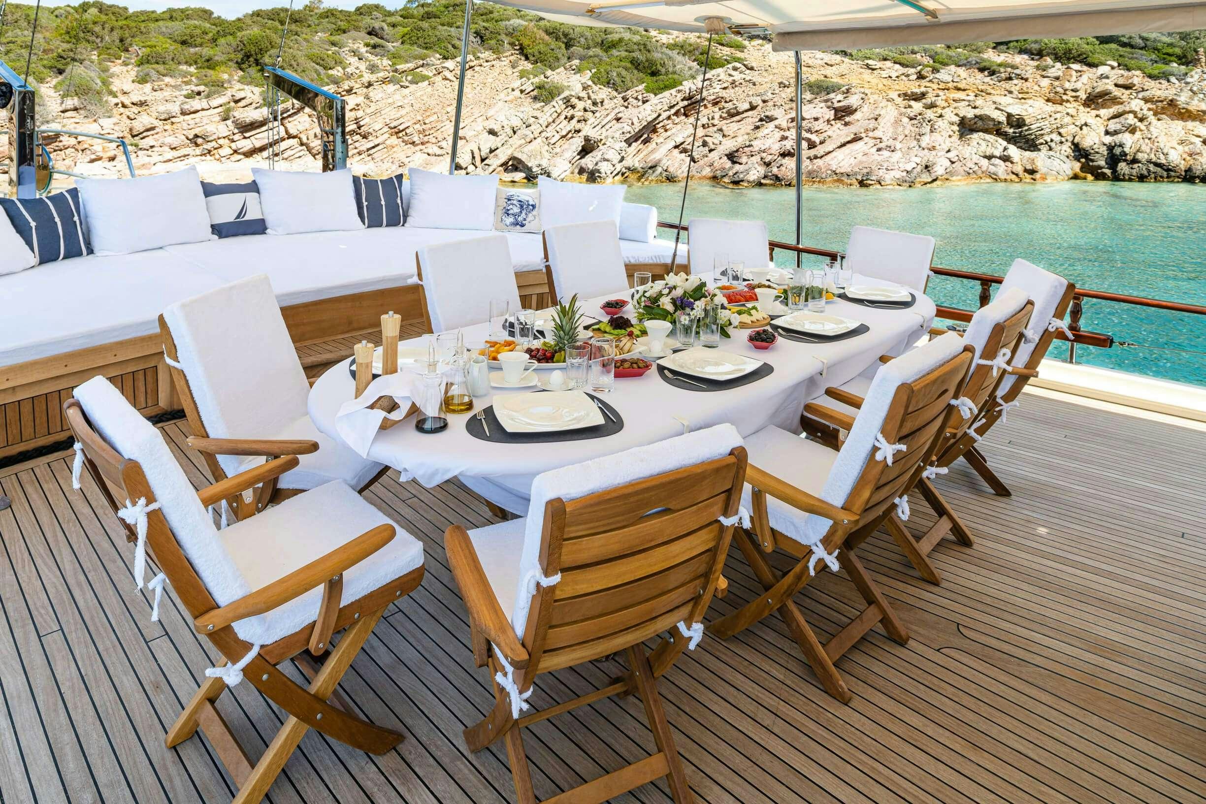 a table set with chairs and a pool in the background aboard ESTRELLA DE MAR Yacht for Charter