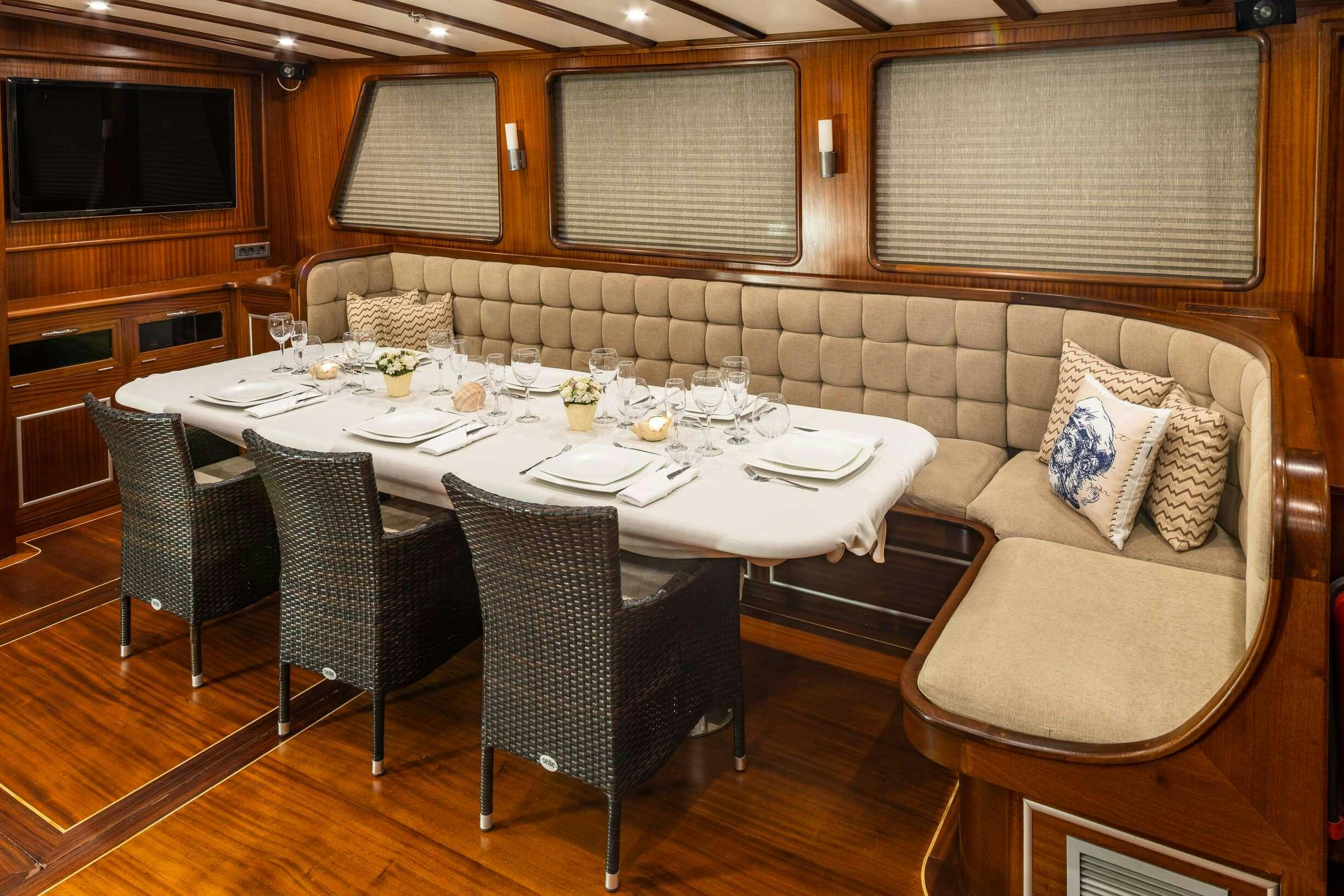 a dining table and chairs in a room with a couch and a television aboard ESTRELLA DE MAR Yacht for Charter