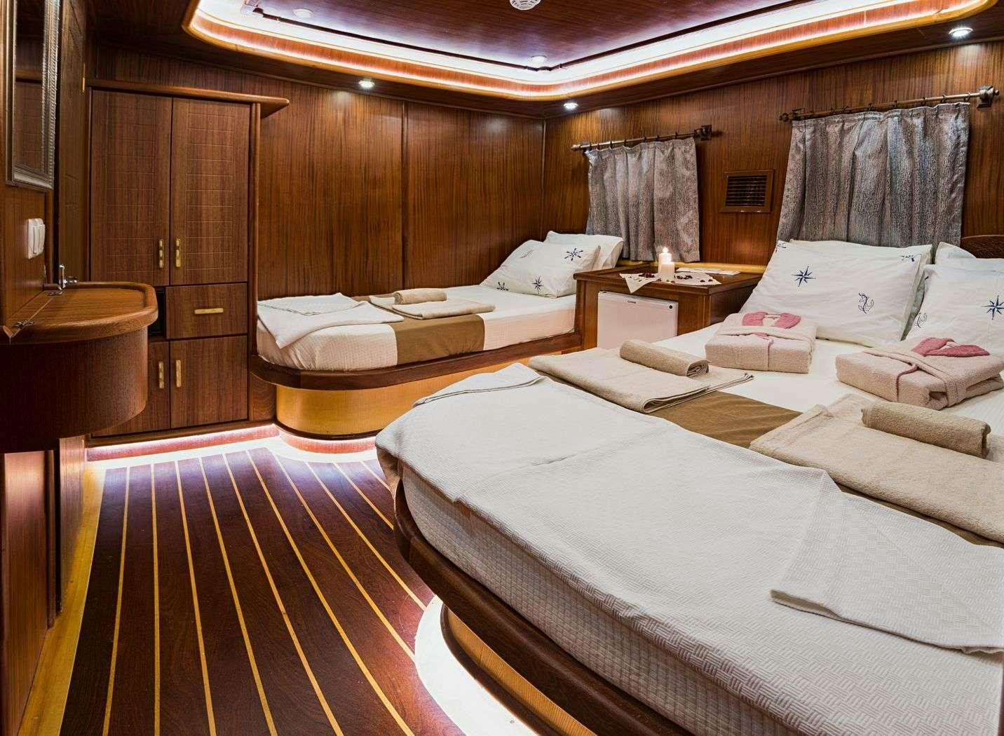 a room with beds and a table aboard S NUR TAYLAN Yacht for Charter