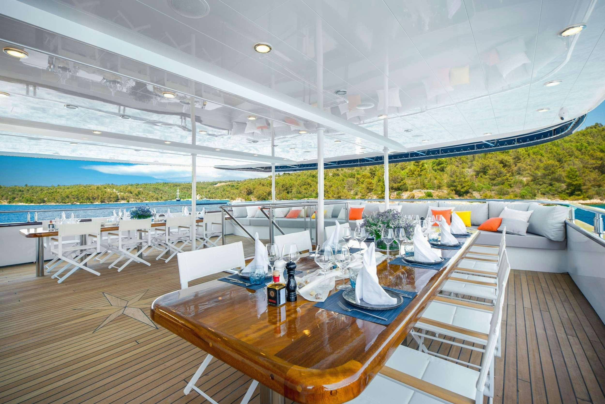 a deck with a table and chairs aboard AGAPE ROSE Yacht for Charter