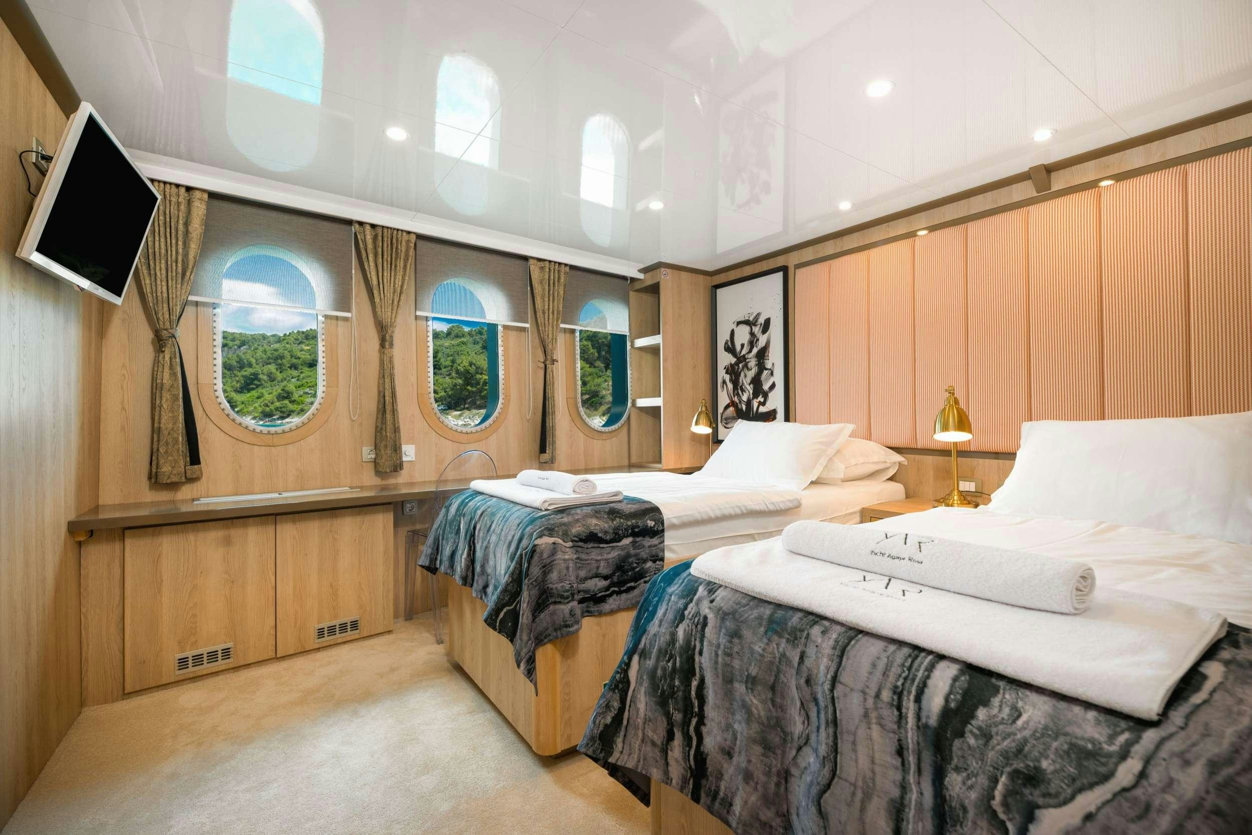 a room with beds and a tv aboard AGAPE ROSE Yacht for Charter