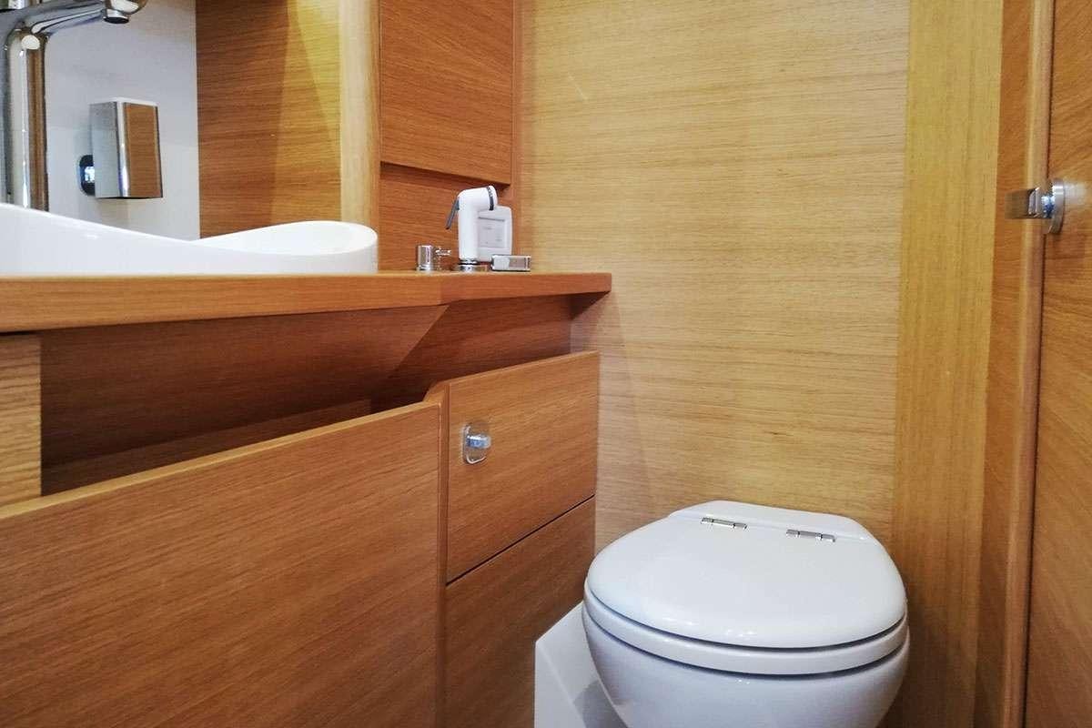 a bathroom with a toilet and a mirror aboard Futura Yacht for Charter