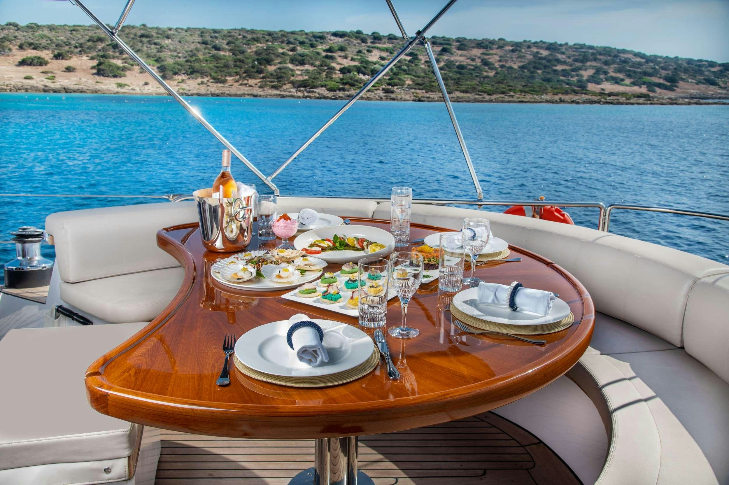 a table with plates and glasses on it next to a body of water aboard SPIRIT L Yacht for Charter