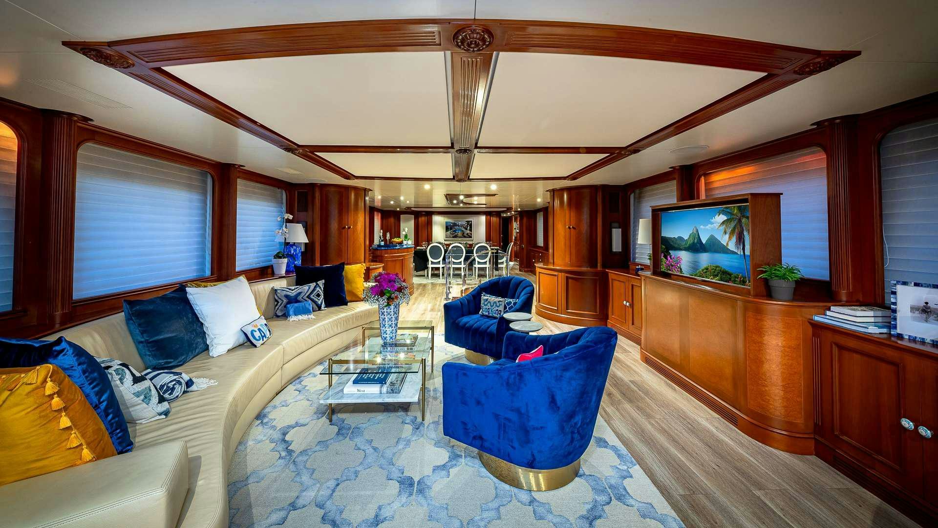 a living room with a blue couch and a television aboard POUR ANOTHER Yacht for Charter