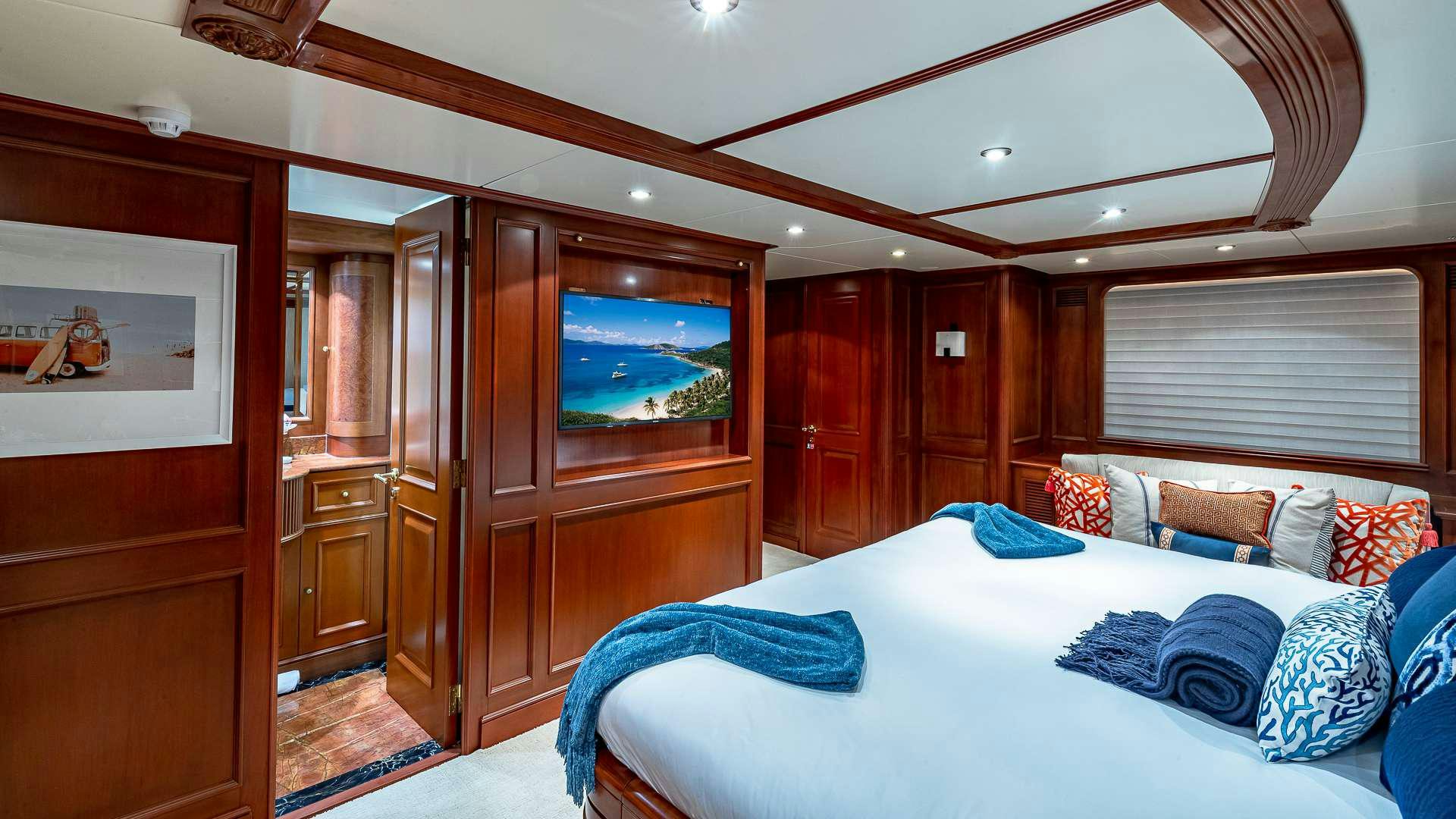 a bedroom with a bed and a wood cabinet aboard POUR ANOTHER Yacht for Charter