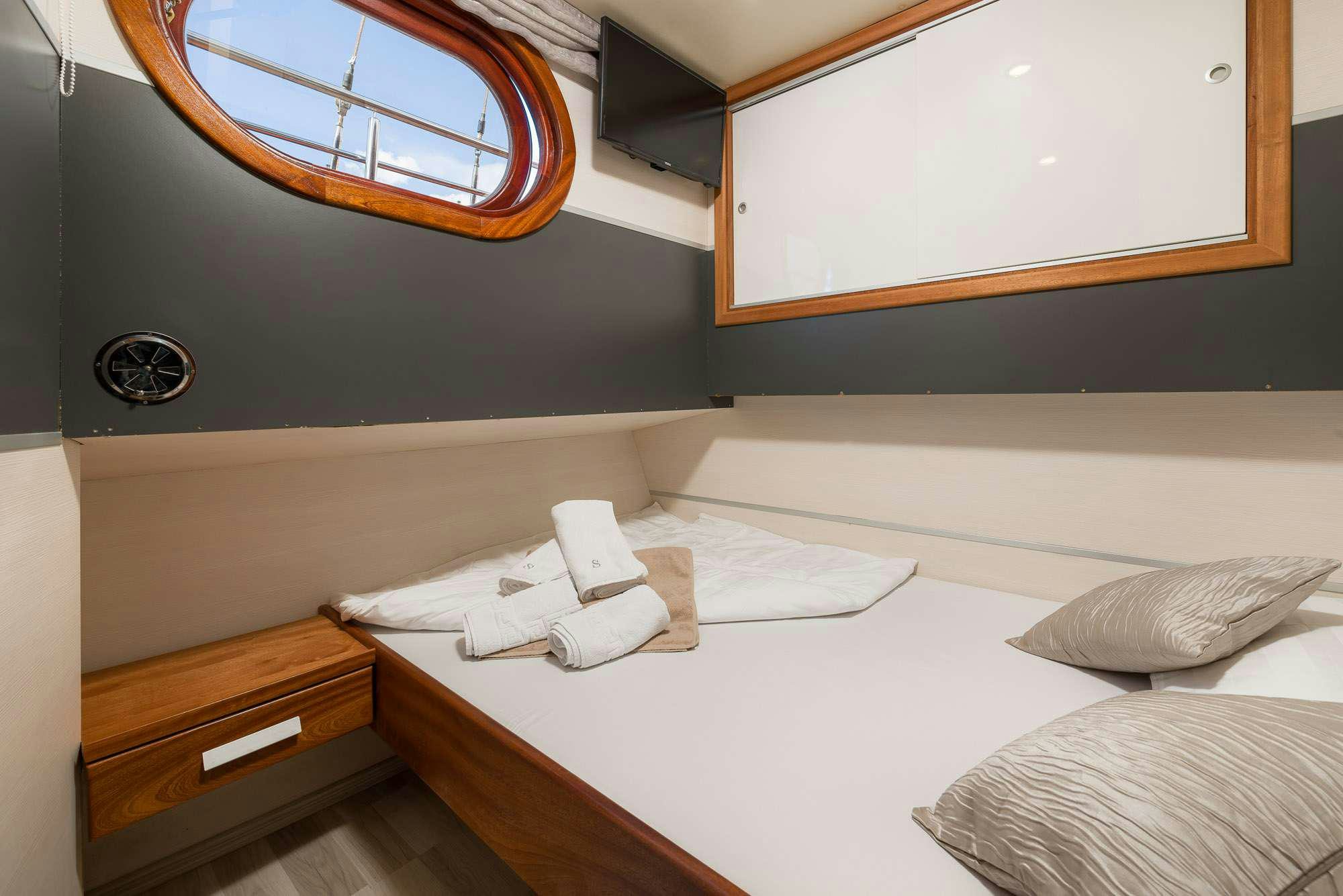 a bed with a white bed spread aboard SLANO Yacht for Charter
