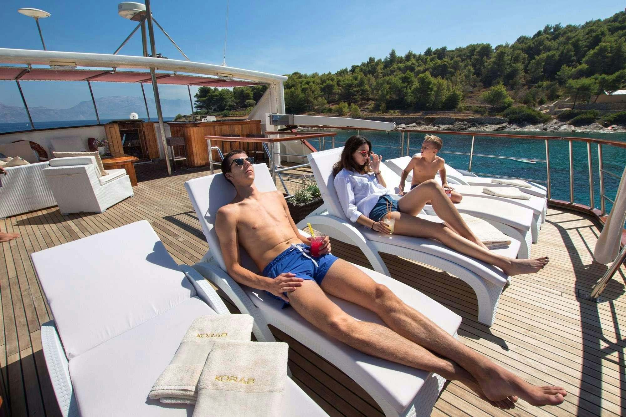 a group of people sitting on a lounge chair on a deck aboard KORAB Yacht for Charter