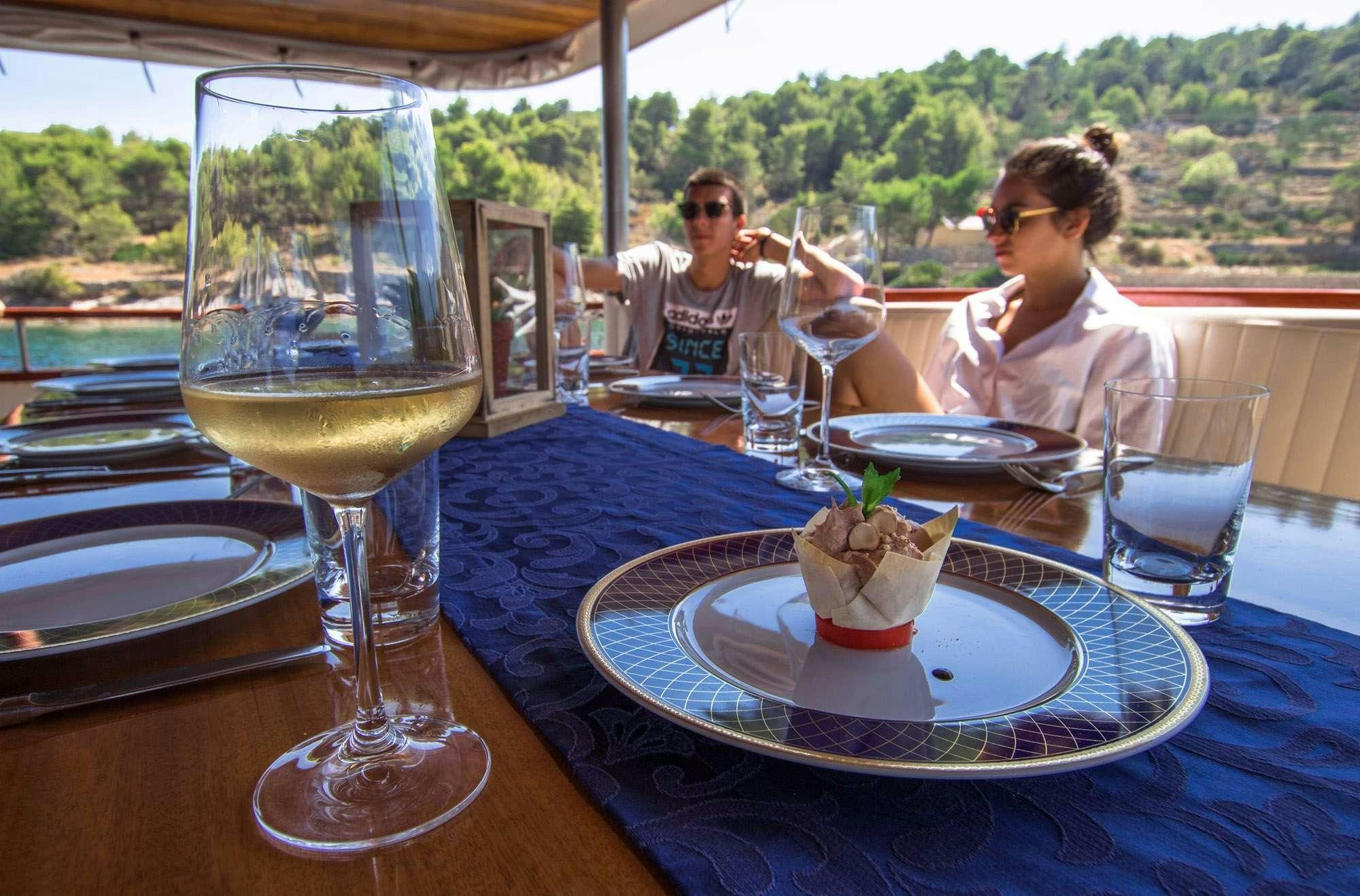 a couple of people sitting at a table with food and wine glasses aboard KORAB Yacht for Charter