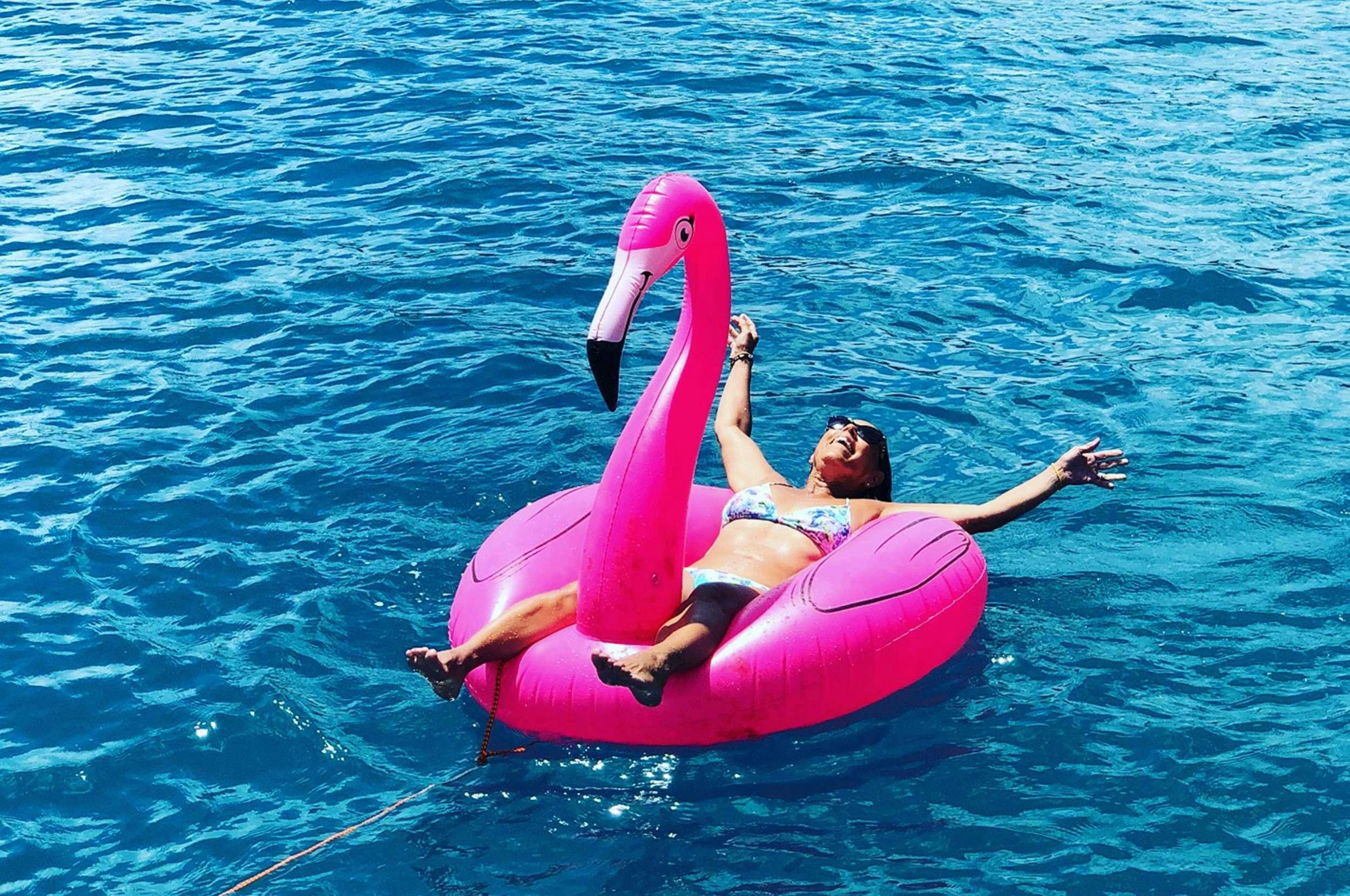 a man floating on a pink floaty in the water aboard Genesis II Yacht for Charter
