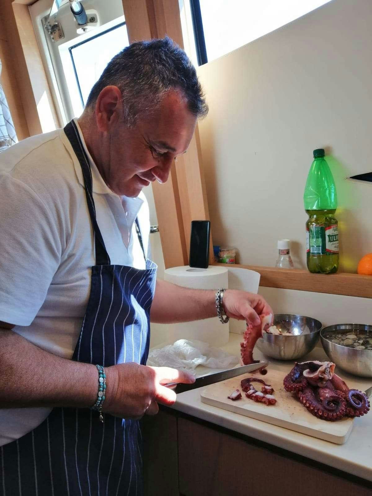 a man in a kitchen preparing food aboard JOY Yacht for Charter