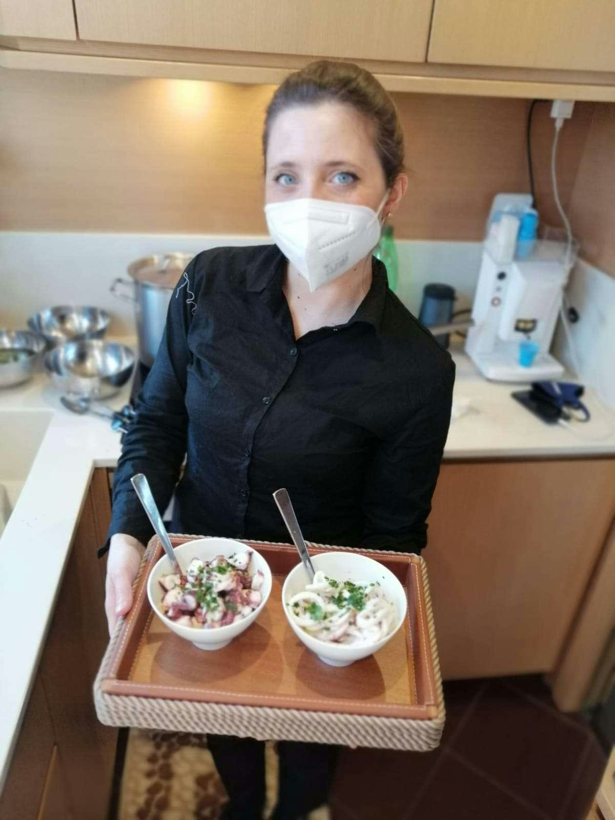 a woman wearing a mask and holding a bowl of food aboard JOY Yacht for Charter