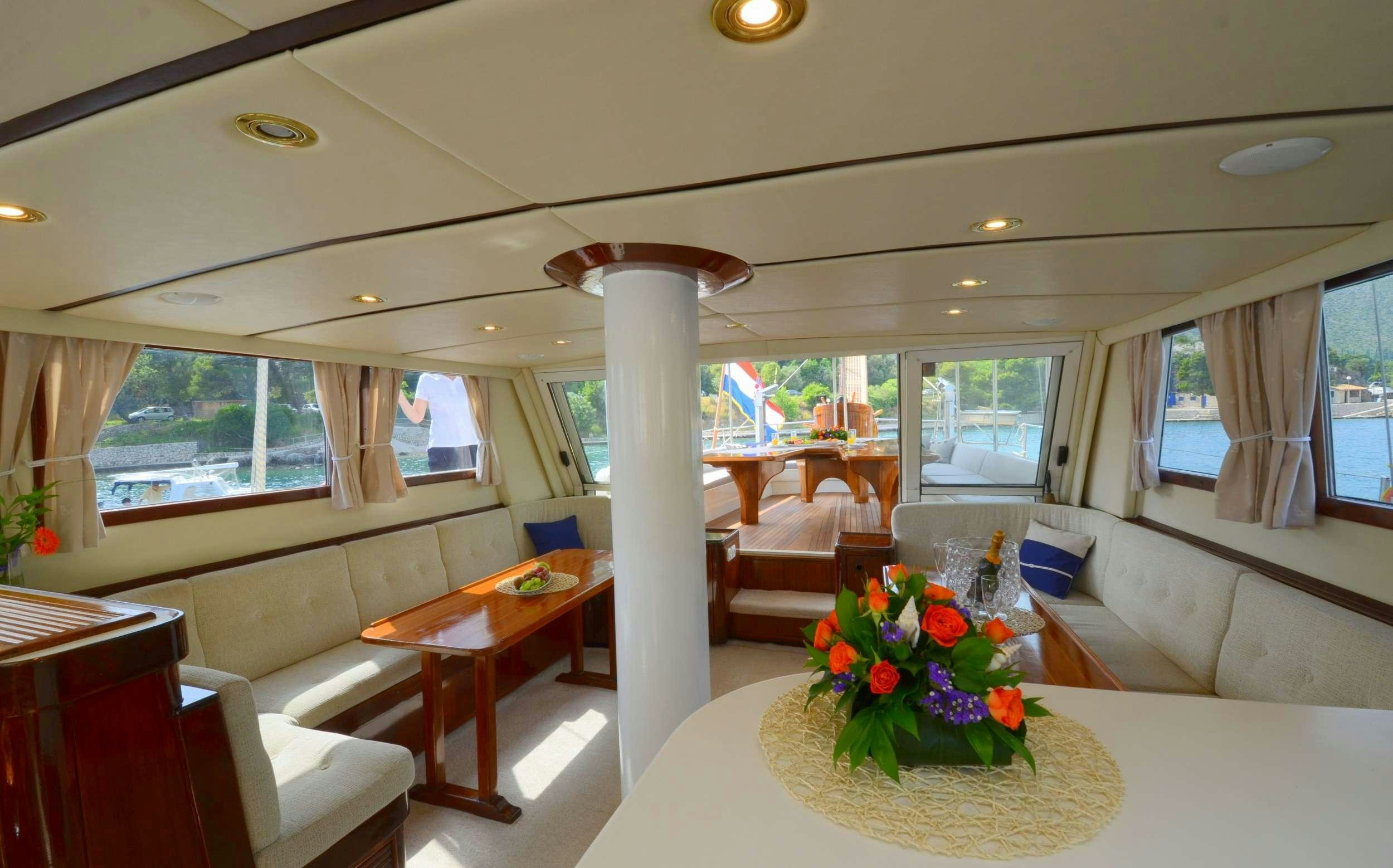a large room with a table and chairs and a large window aboard FORTUNA Yacht for Charter