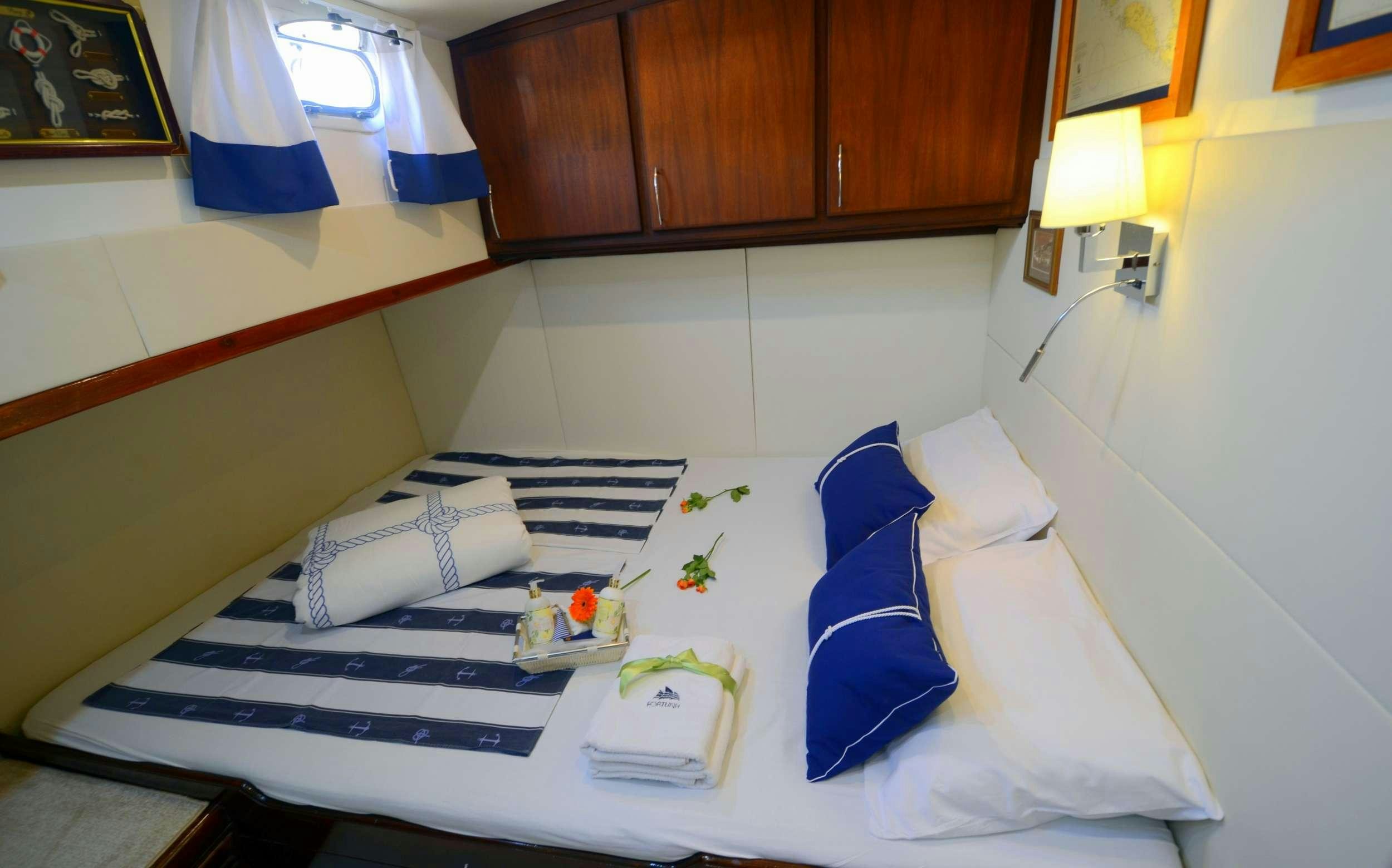 a room with a bed and a desk aboard FORTUNA Yacht for Charter