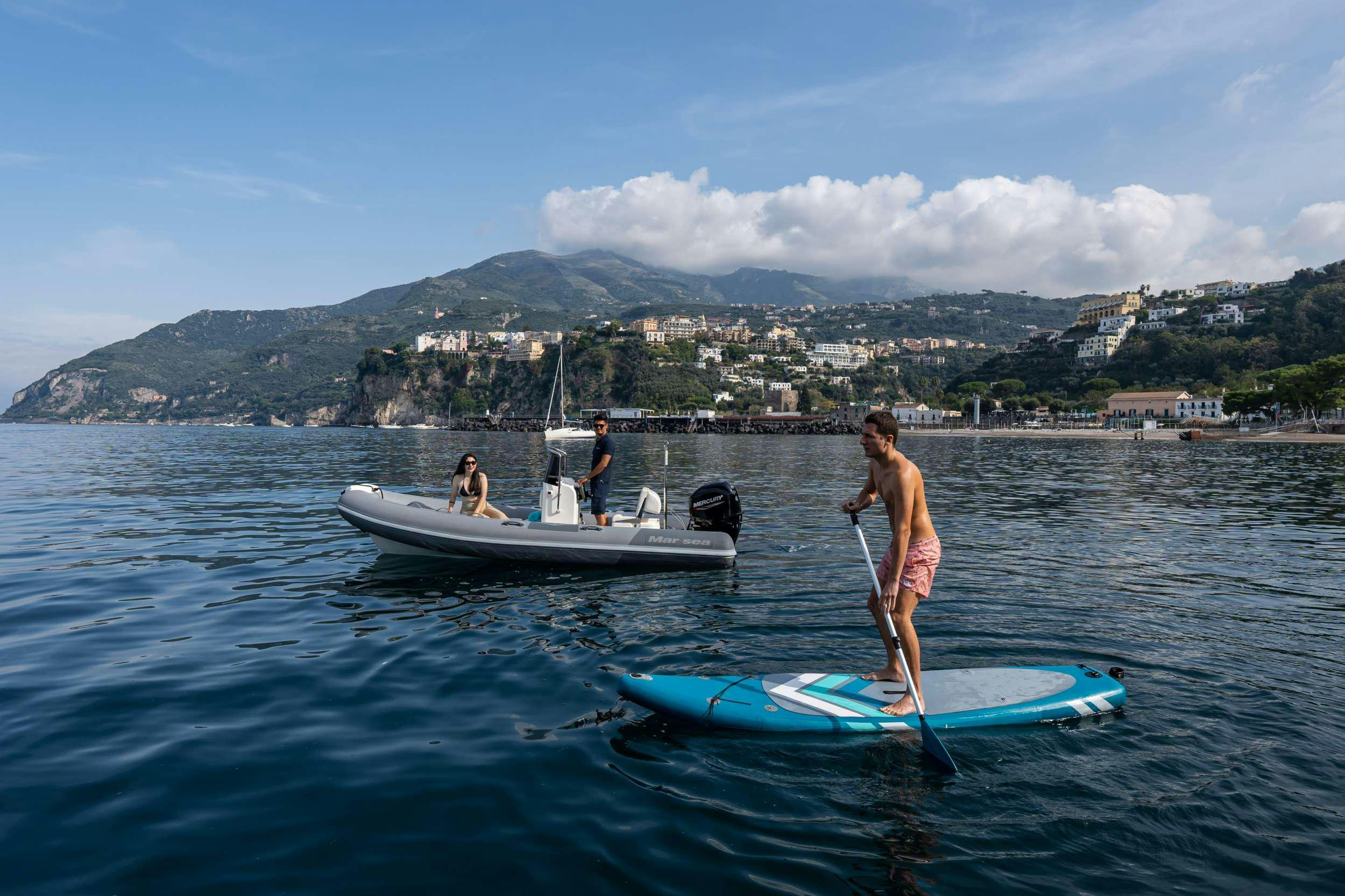 a person on a paddle board next to a boat with a paddle aboard RESILIENCE Yacht for Charter