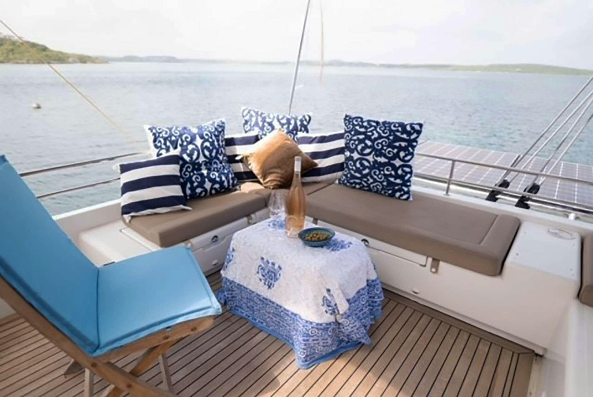 a boat with pillows and a chair on a deck with a blue chair and a bottle on it aboard THE RECIPE Yacht for Charter