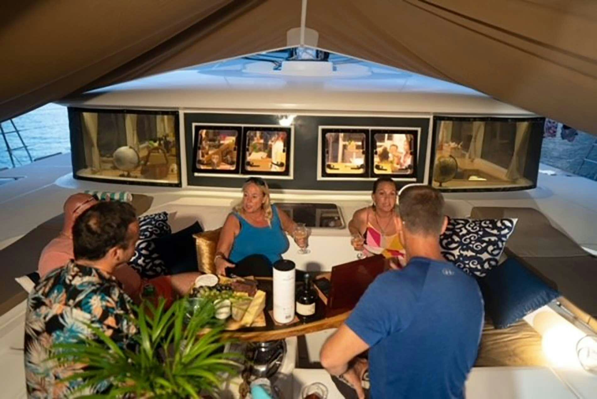 a group of people sitting around a table in a tent aboard THE RECIPE Yacht for Charter