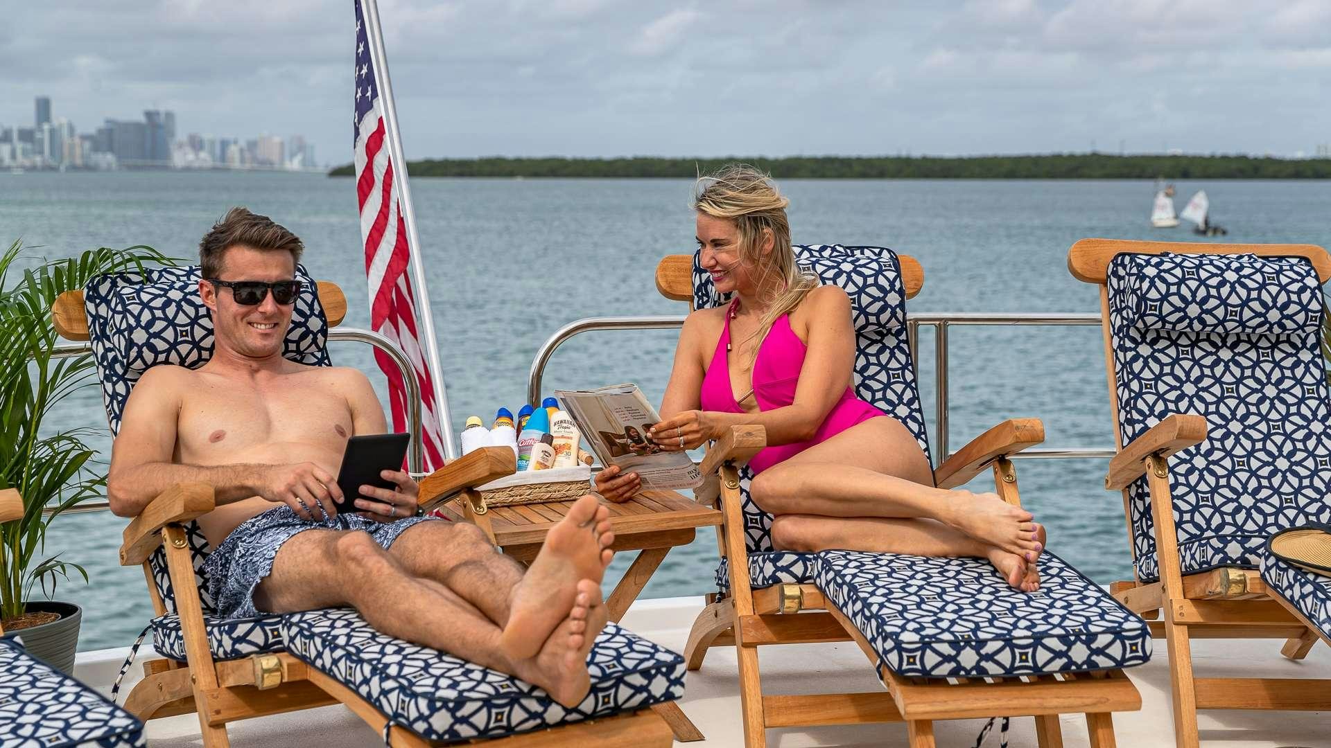 a man and woman sitting on a chair at a table with a flag aboard SAFARI Yacht for Charter