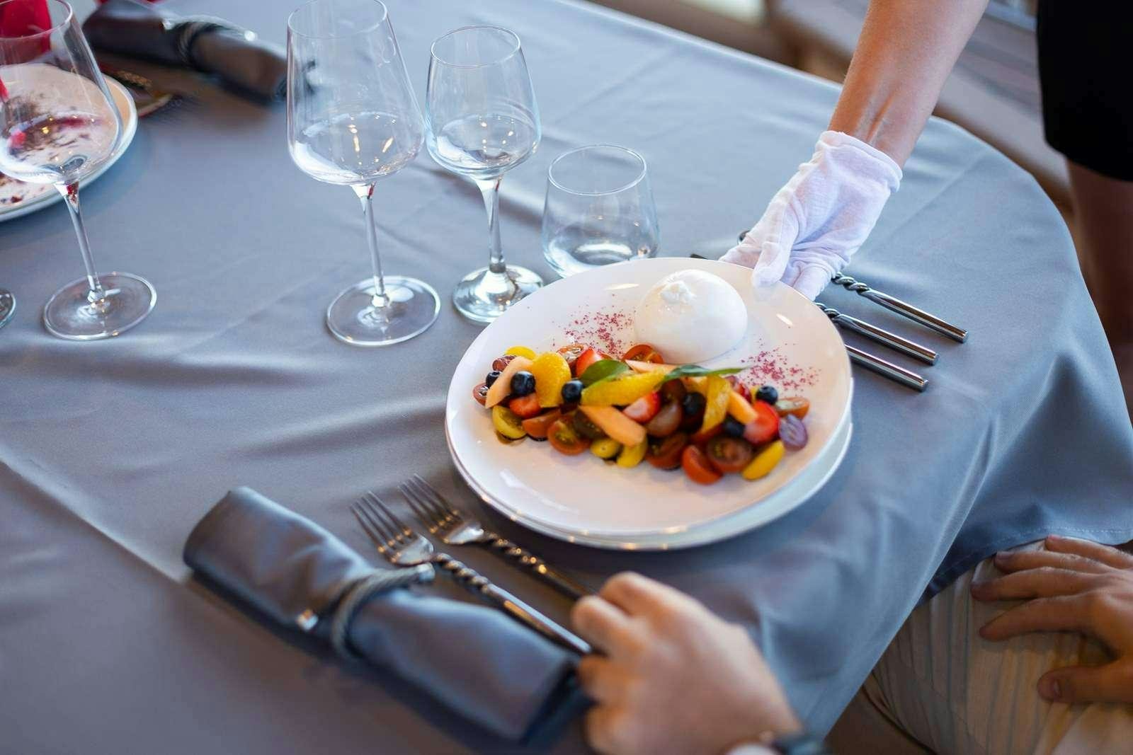 a plate of food and glasses aboard GALLANT Yacht for Charter