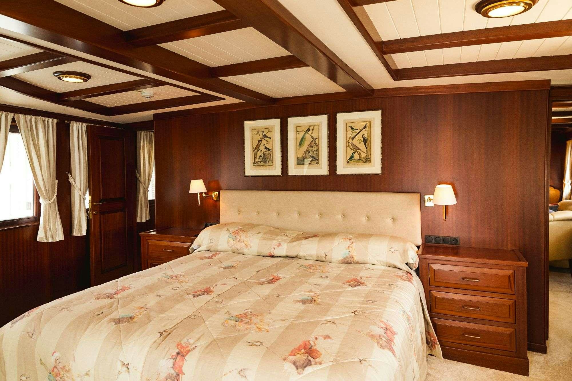 a bedroom with a bed and a dresser aboard HALAS 71 Yacht for Charter