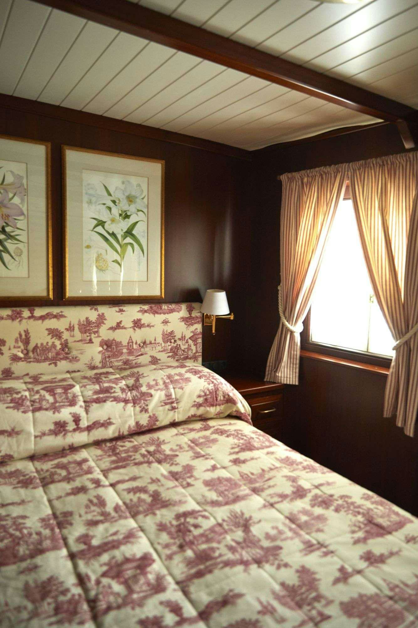 a bedroom with a bed and a window aboard HALAS 71 Yacht for Charter