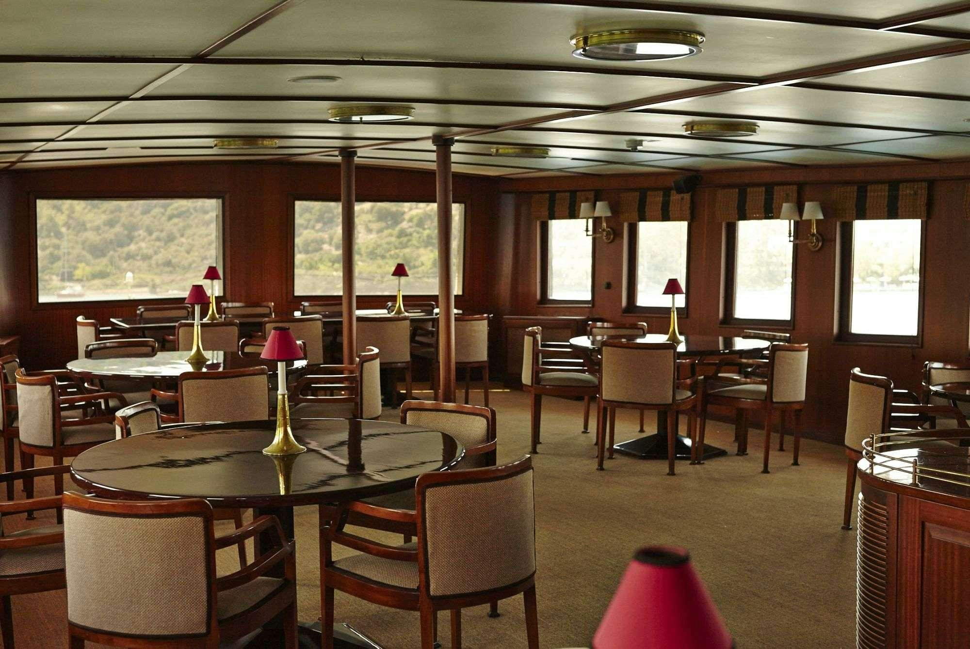 a room with tables and chairs aboard HALAS 71 Yacht for Charter