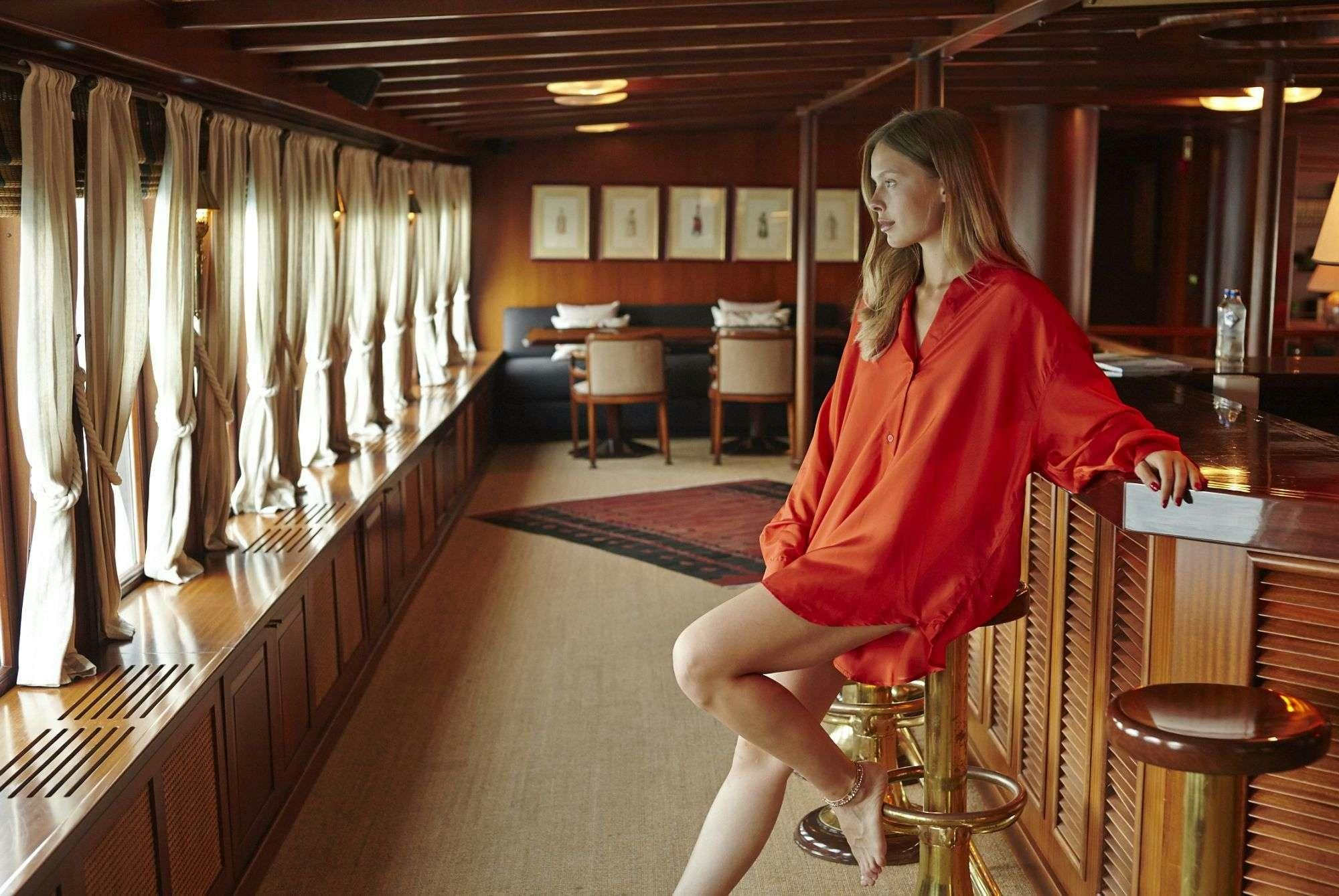 a woman in a red dress sitting on a bar stool aboard HALAS 71 Yacht for Charter