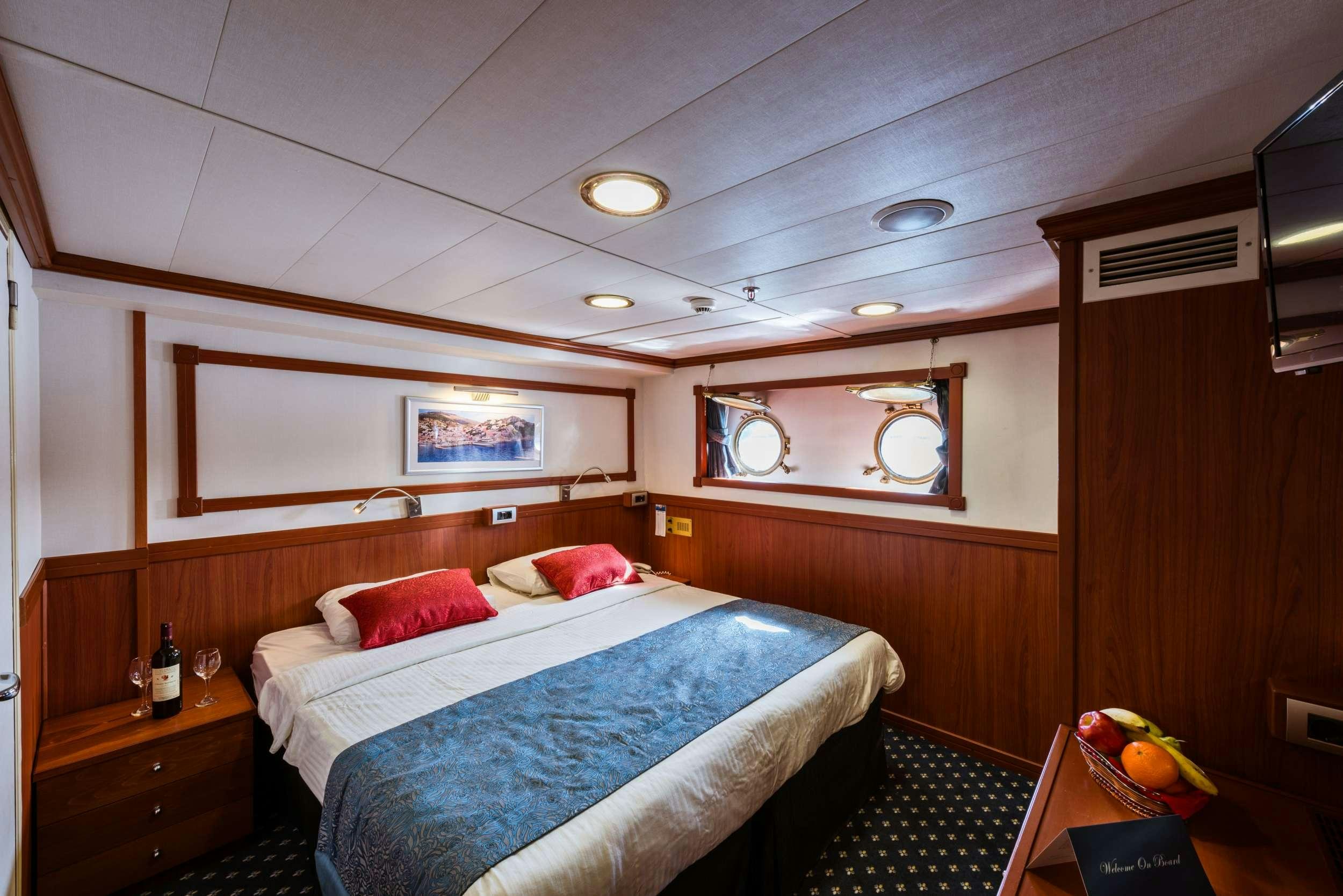 a room with a bed and a desk aboard GALILEO Yacht for Charter