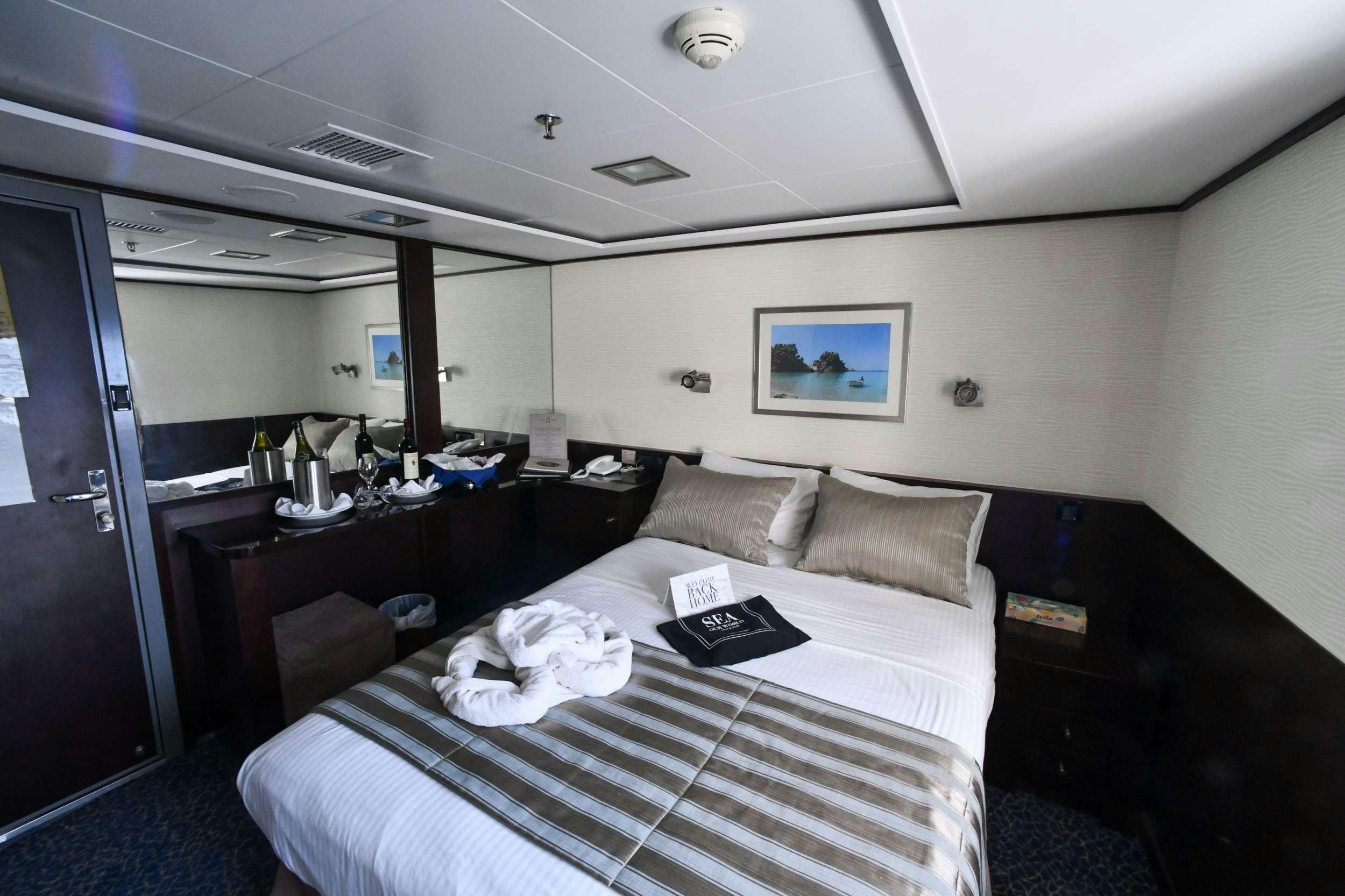 a bedroom with a bed and desk aboard HARMONY V Yacht for Charter