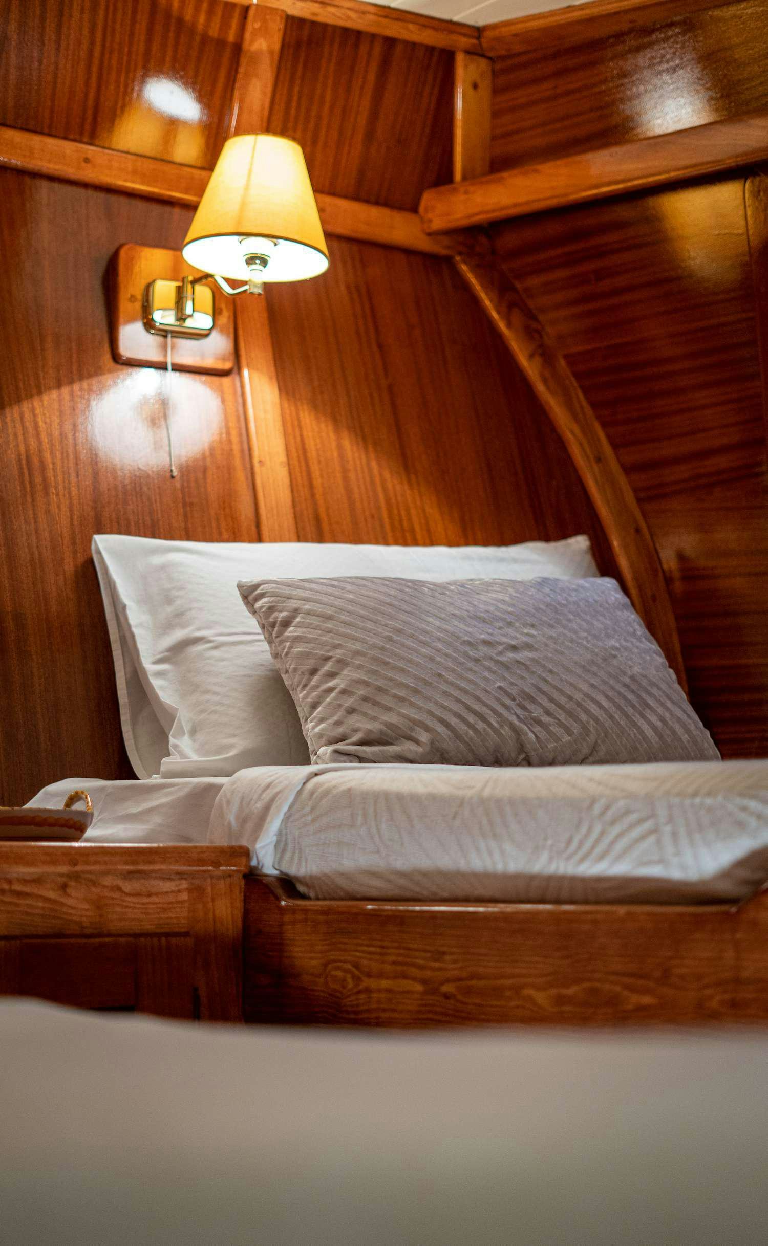 a bed with a lamp on it aboard MYRA Yacht for Charter