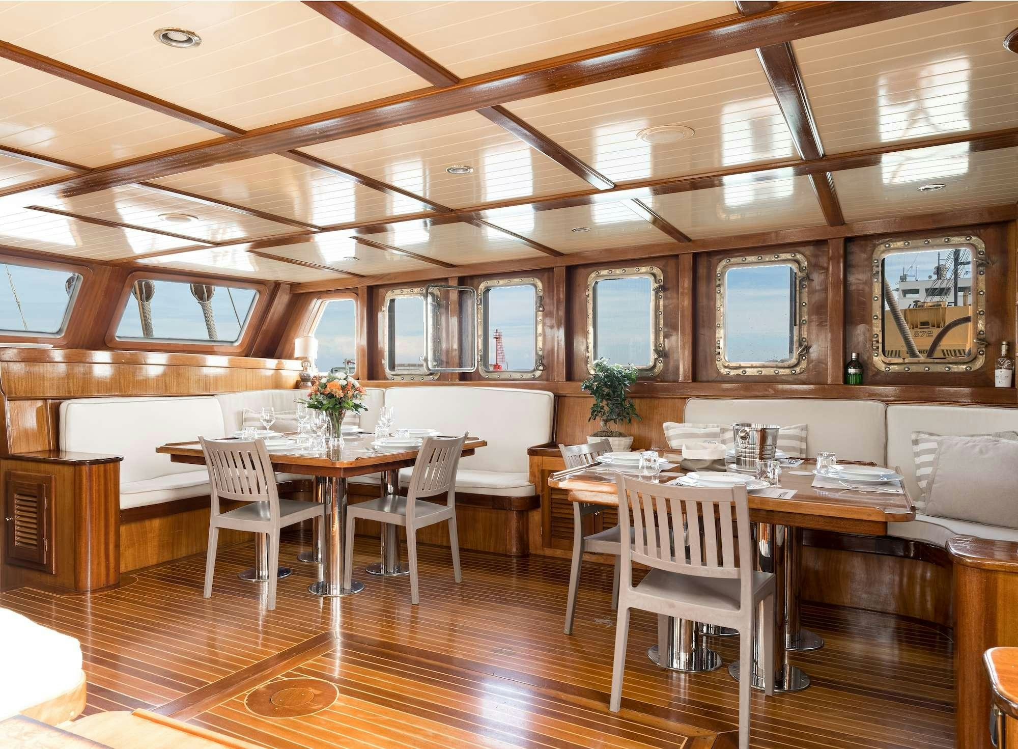 a room with tables and chairs aboard MYRA Yacht for Charter