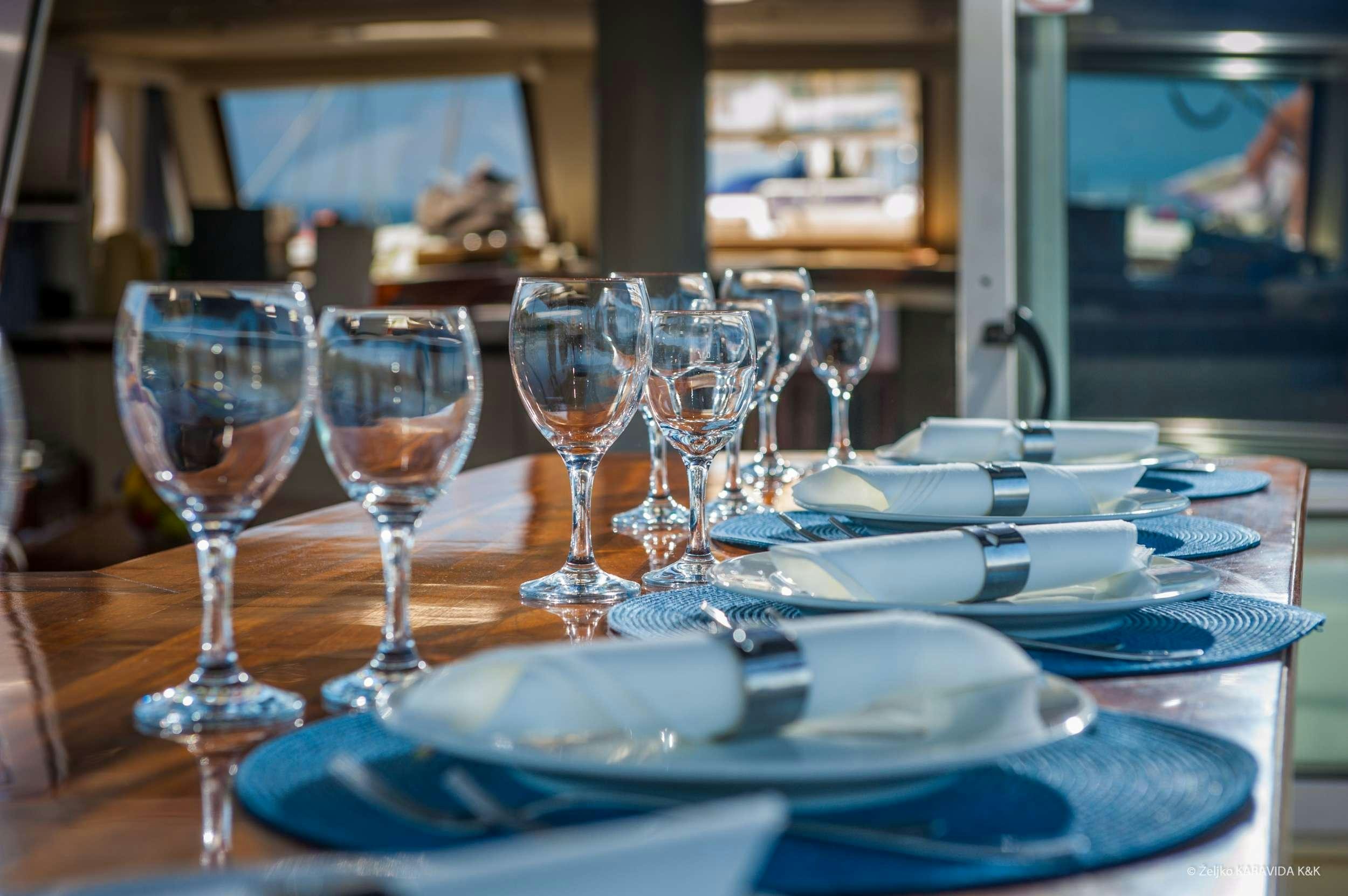 a table with wine glasses and plates aboard FORTUNA Yacht for Charter