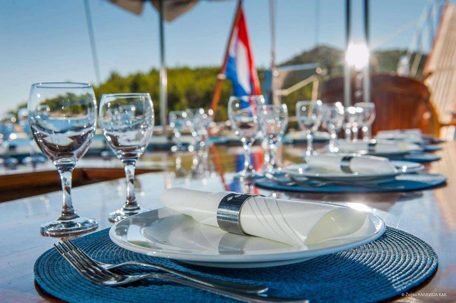 a table with plates and glasses aboard FORTUNA Yacht for Charter