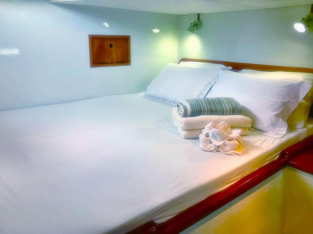 a bed with white sheets and pillows aboard QUEST Yacht for Charter
