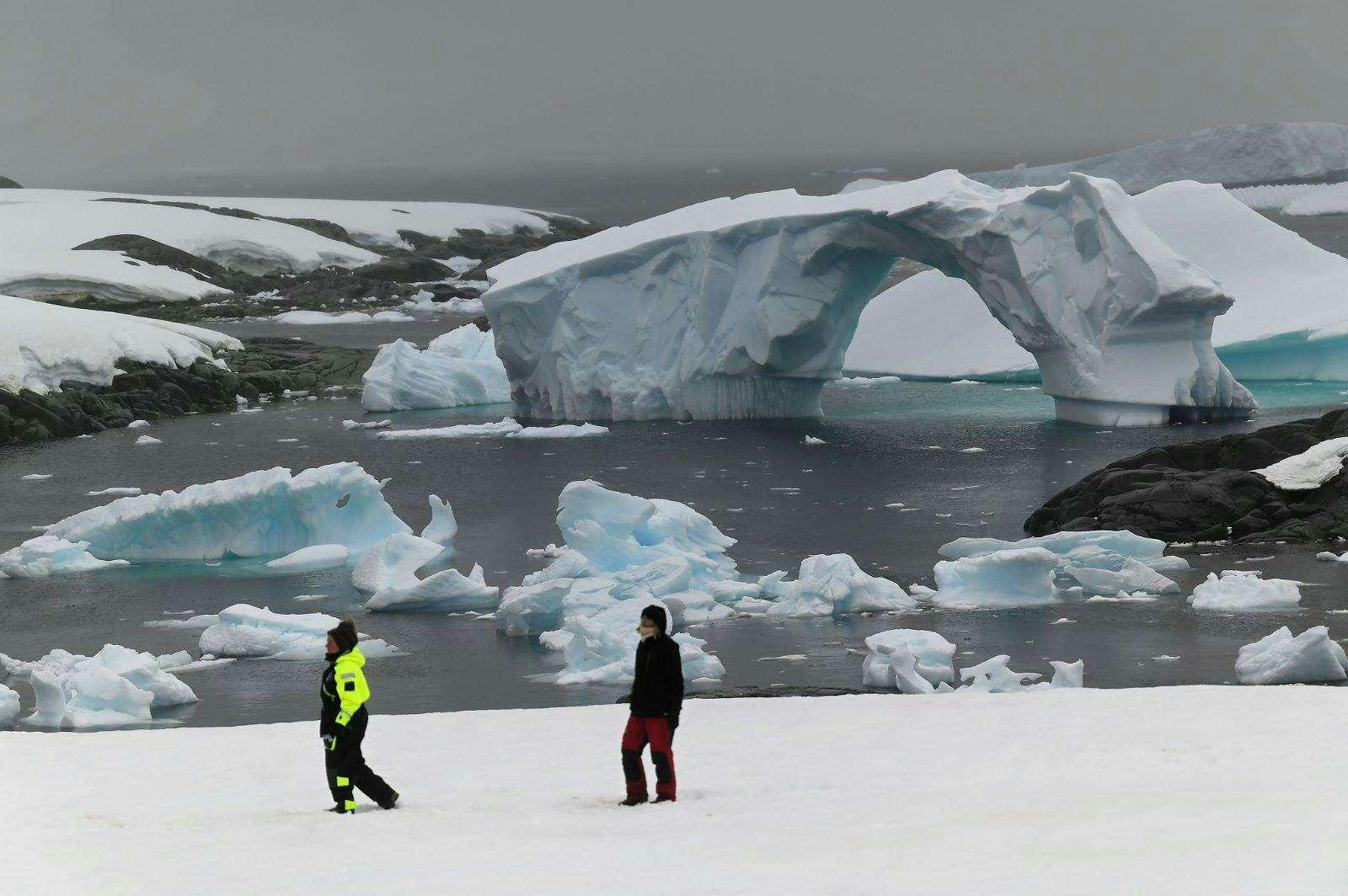 two people standing in front of an iceberg aboard TANANA Yacht for Charter