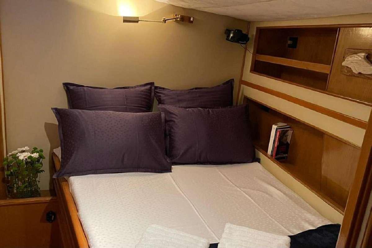 a bed with purple pillows aboard TANANA Yacht for Charter