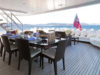 a table set with chairs and umbrellas on a deck aboard MY LITTLE VIOLET Yacht for Charter