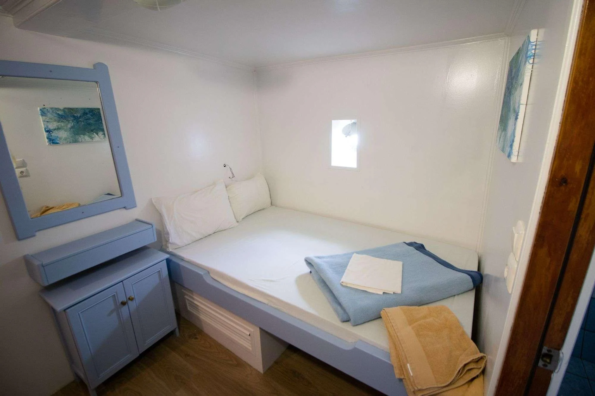 a bedroom with a bed and a dresser aboard AEGEOTISSA II Yacht for Charter