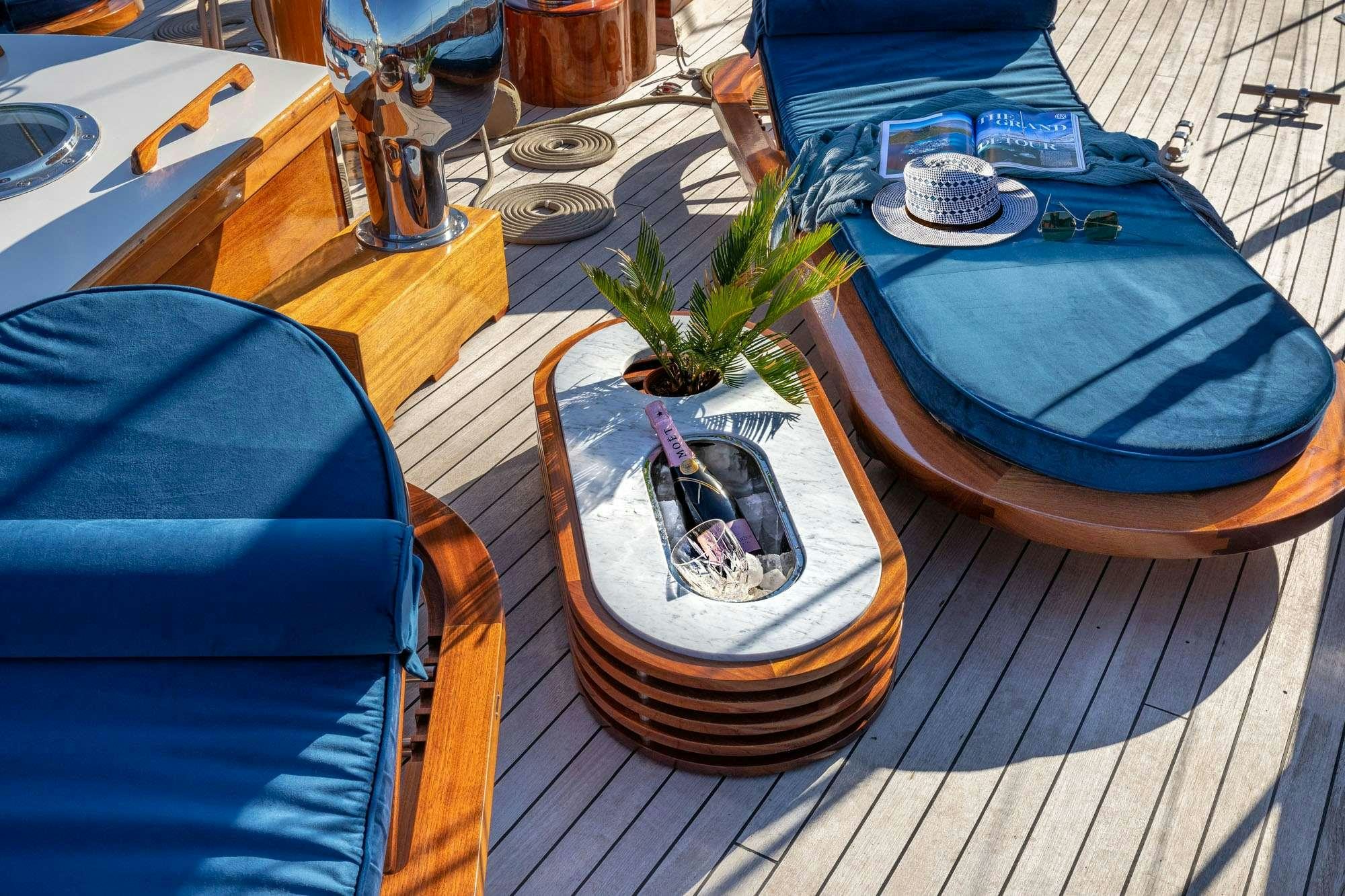 a table with a blue chair and a blue chair with a blue chair and a plant on it aboard WEATHER BIRD Yacht for Charter