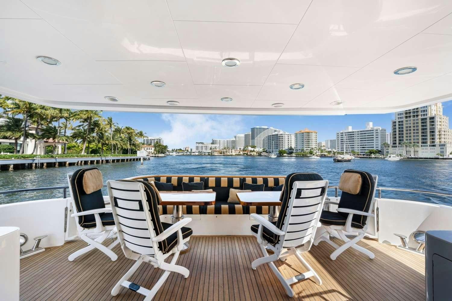 a deck with chairs and a body of water and a city in the background aboard SEAS TO SEE Yacht for Charter