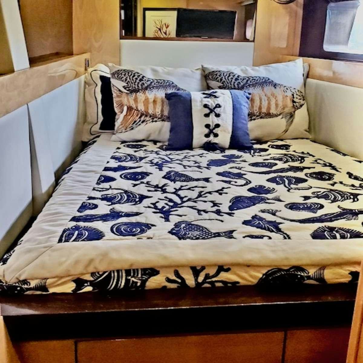 a bed with a blue and white comforter and pillows aboard SERENDIPITY Yacht for Charter