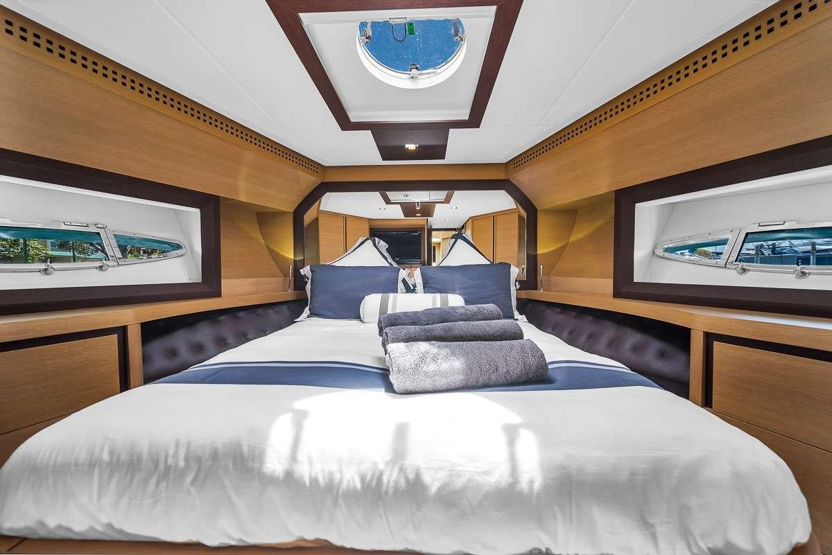 a bed with a white sheet and a blue pillow on it aboard VANTAGE Yacht for Charter