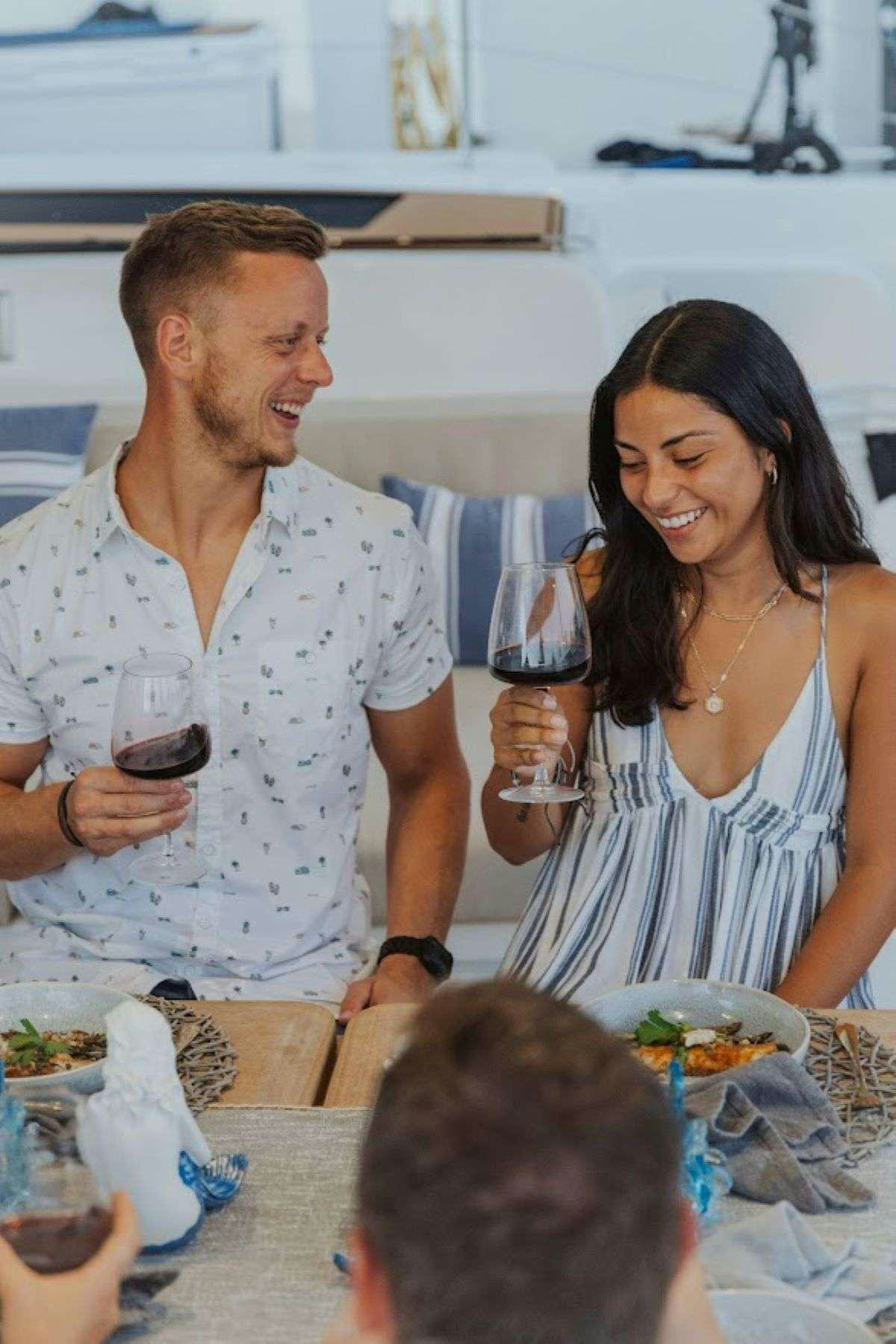 a man and woman sitting at a table with food and drinks aboard Purely Blu Yacht for Charter