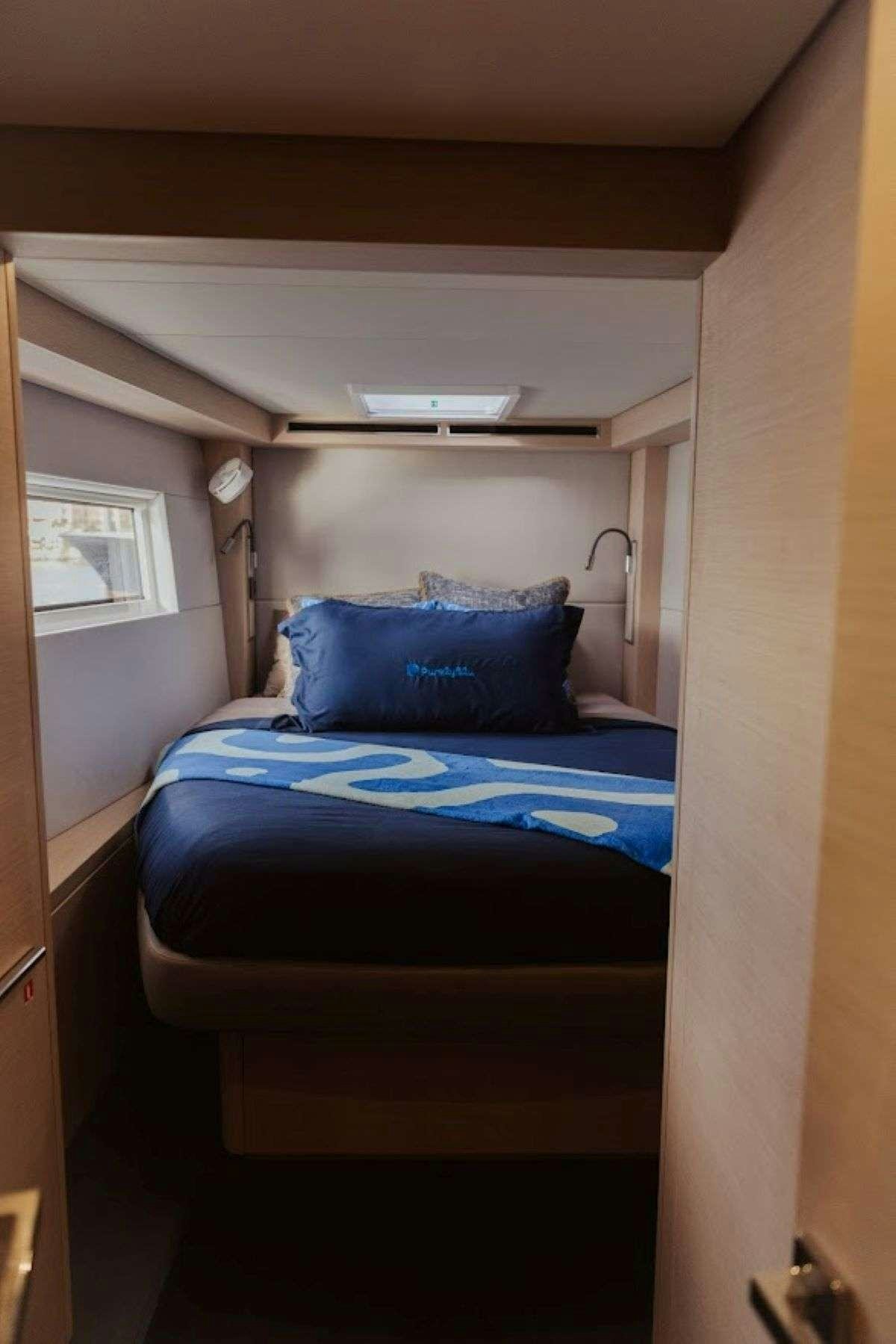 a bed with blue sheets aboard Purely Blu Yacht for Charter